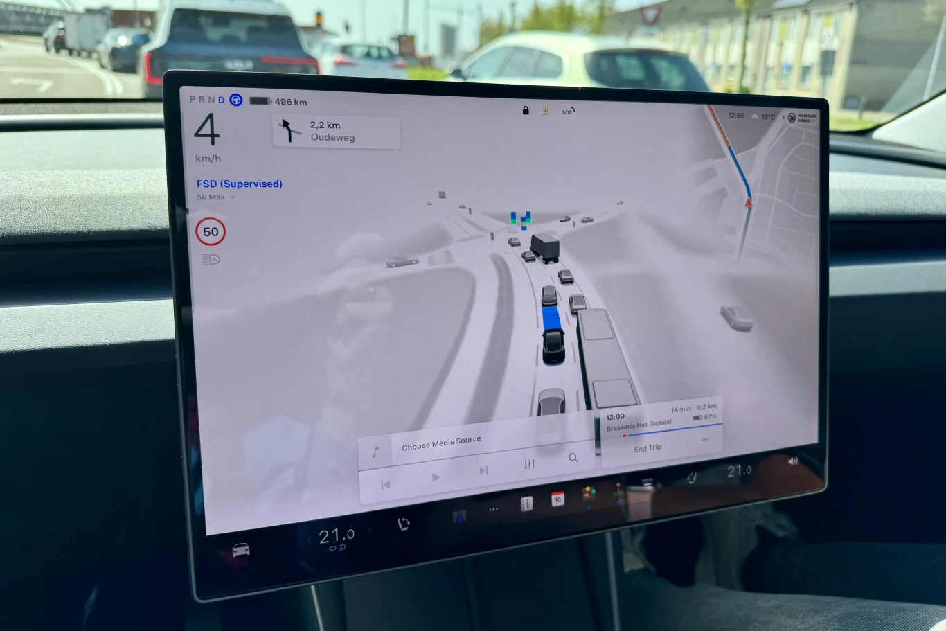 duży ekran dotykowy samochodu Tesla z wyświetloną nawigacją, widokiem mapy 3D najbliższego otoczenia pojazdu oraz szczegółowymi informacjami o trasie, ograniczeniu prędkości i aktywnej funkcji autopilota