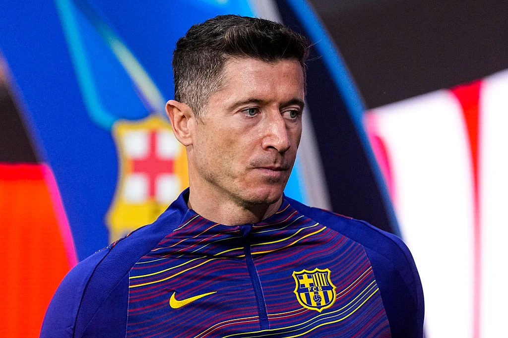 Robert Lewandowski Robert Lewandowski w stroju FC Barcelony z widocznym herbem na tle rozmytego wielobarwnego logo klubu