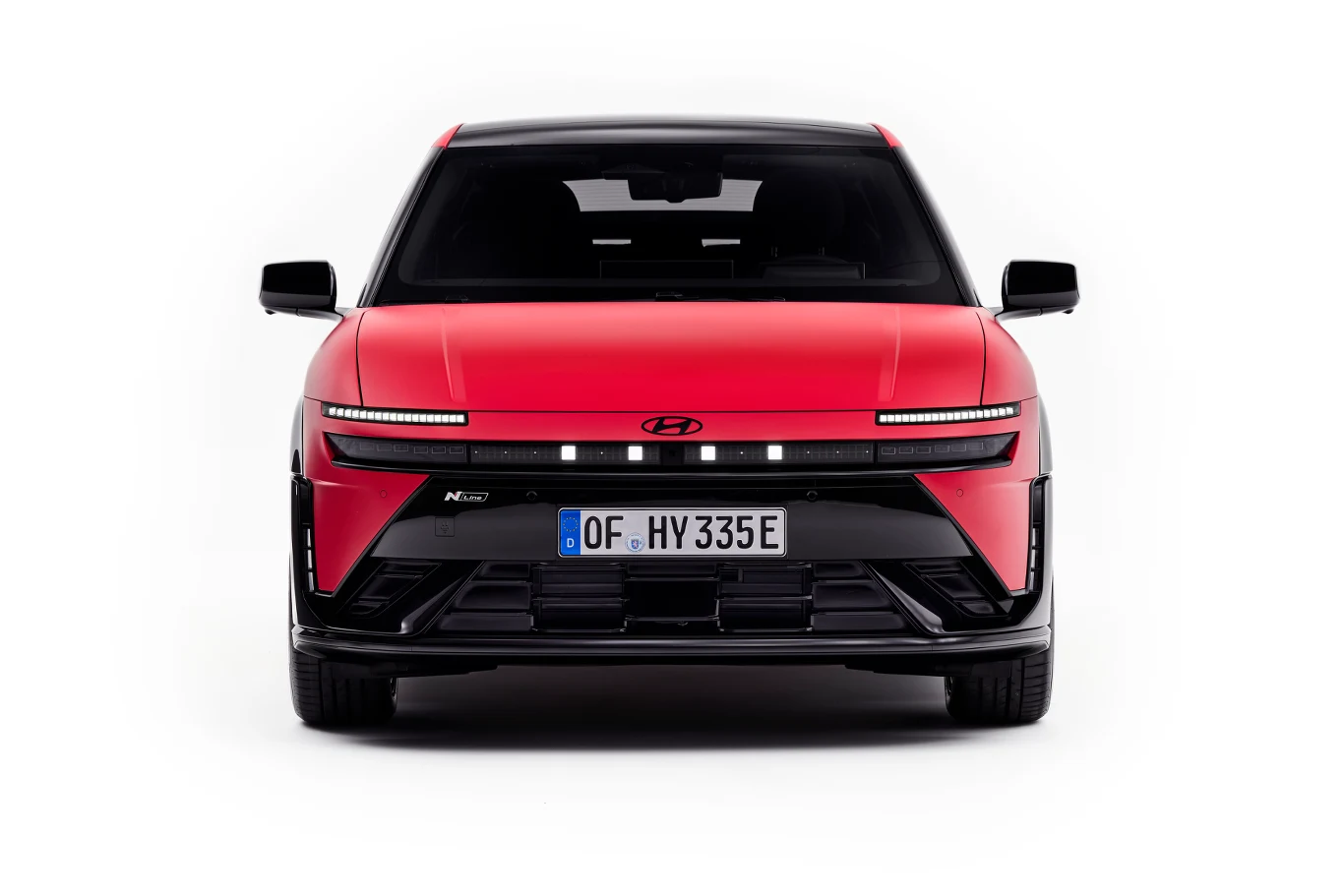 Hyundai Ioniq 3 Czerwony samochód Hyundai z czarnym dachem, szerokim czarnym grillem i wąskimi poziomymi reflektorami LED, widoczny enface na białym tle, z wyeksponowaną tablicą rejestracyjną OF HY 335E.
