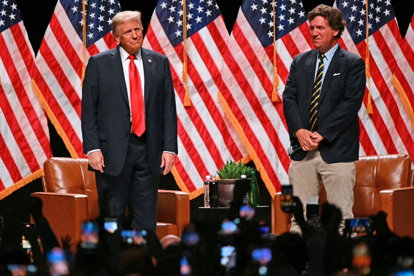 Tucker Carlson żałuje, że poparł Donalda Trumpa w wyborach prezydenckich Tucker Carlson i Donald Trump stoją na scenie, w tle amerykańskie flagi. Była gwiazda Fox News odcina się od prezydenta USA.