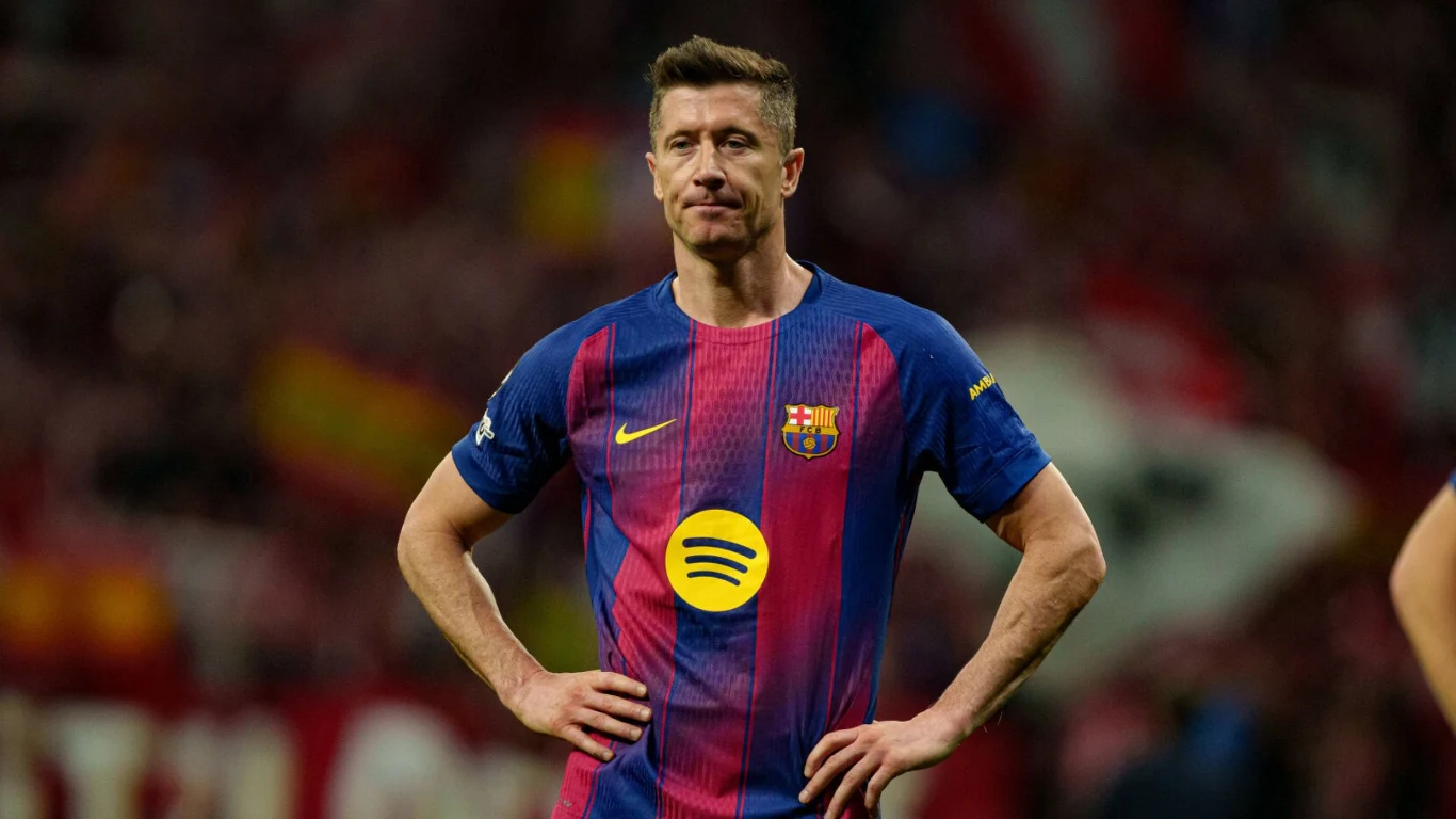 Piłkarz w koszulce FC Barcelony z rękami na biodrach stoi na murawie podczas meczu; na jego twarzy widoczny wyraz skupienia, w tle rozmyte trybuny oraz kibice.