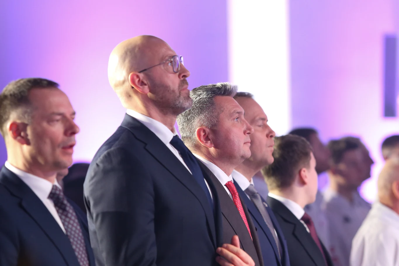 Jakub Rutnicki, Radosław Piesiewicz, Karol Nawrocki Jakub Rutnicki, Radosław Piesiewicz i Karol Nawrocki w garniturach stoją w jasno oświetlonej sali.