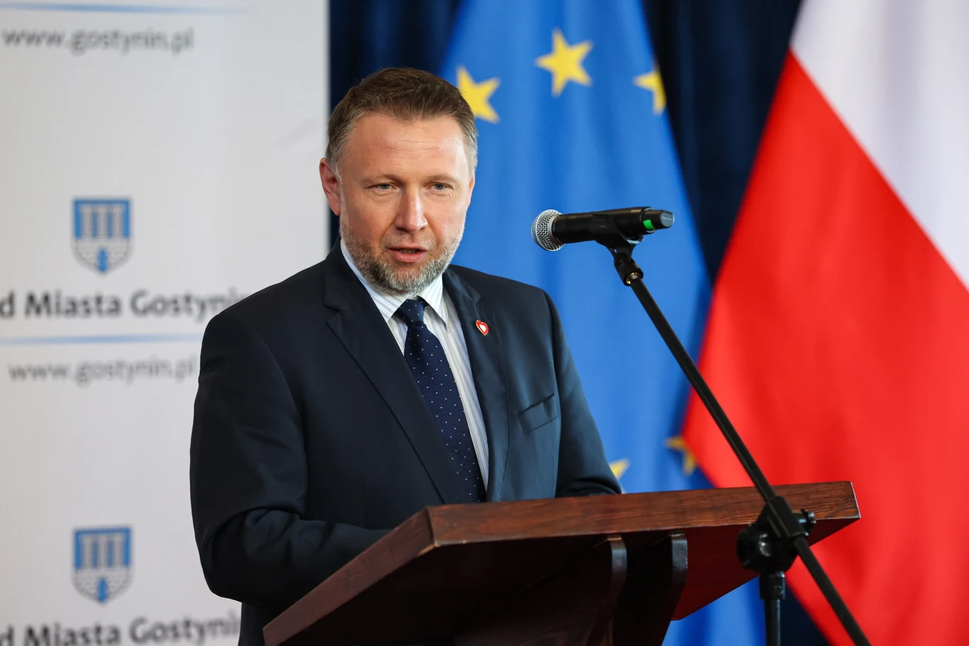 Marcin Kierwiński podczas konferencji w Gostyninie Marcin Kierwiński w garniturze, przemawiający na mównicy.