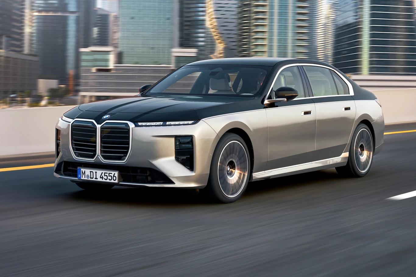 Nowe BMW serii 7 otrzymało zmodernizowany pas przedni BMW serii 7 sedan, dwukolorowe nadwozie, duży grill i reflektory LED, na tle wieżowców, miejska droga