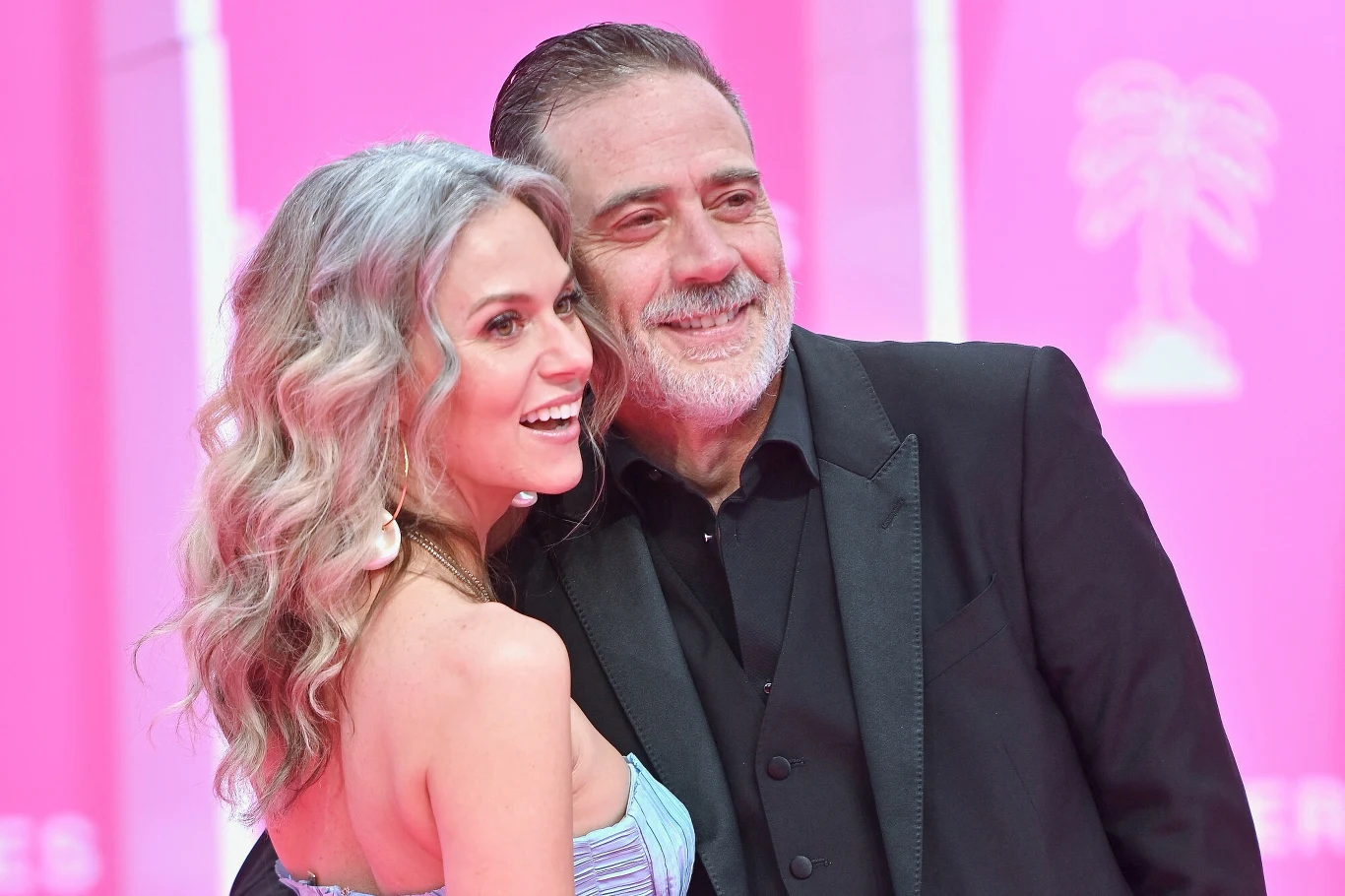 Hilarie Burton z mężem Jeffreyem Deanem Morganem uśmiechnięta para pozująca razem na tle różowej ścianki, kobieta w błękitnej sukni z długimi, falującymi, srebrzystymi włosami, mężczyzna w eleganckim, czarnym garniturze