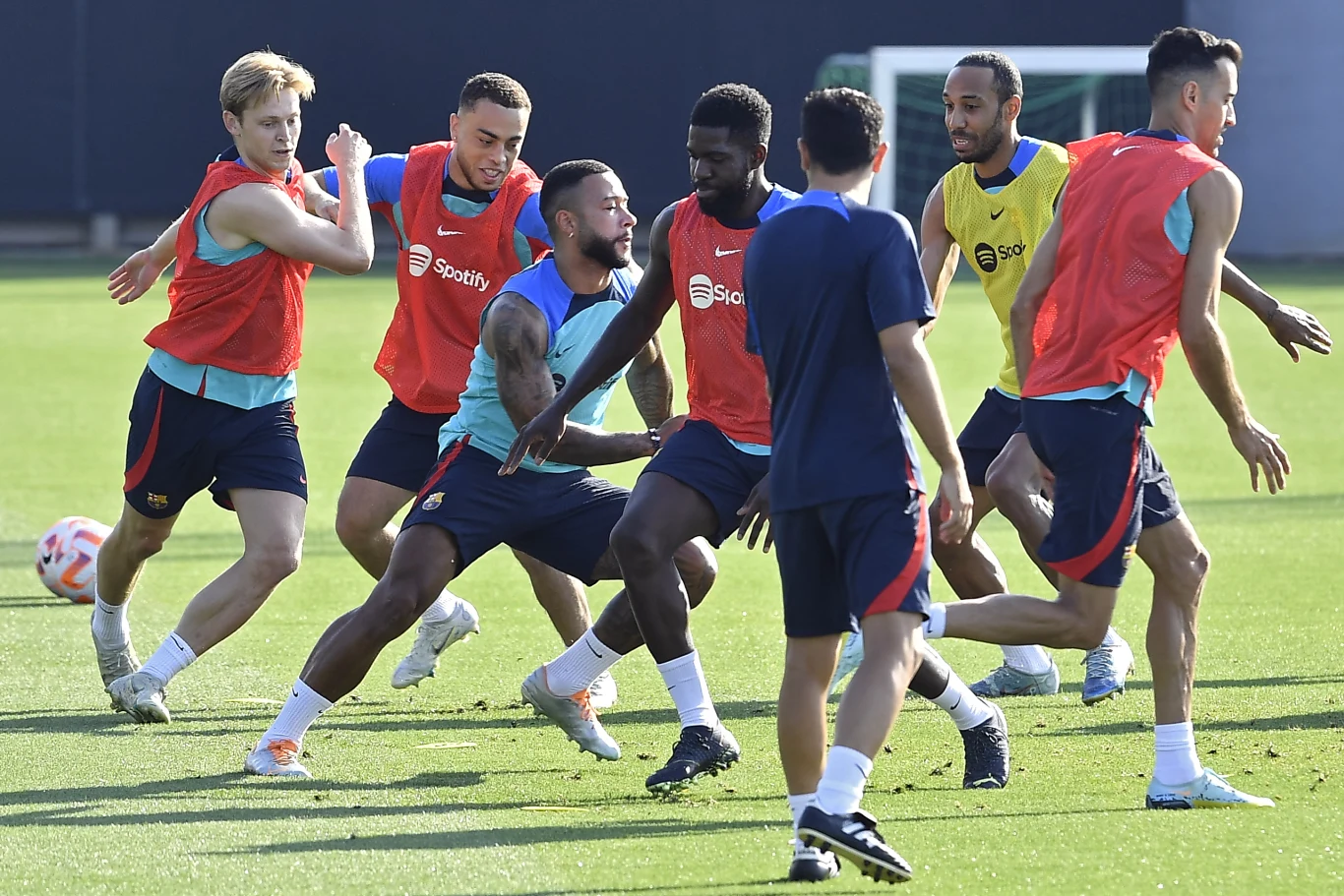 Sergino Dest (drugi z lewej) z chęcią wróciłby do FC Barcelona Sergino Dest (drugi z lewej) trenuje z piłkarzami na boisku; widoczne stroje sportowe, murawa i niebieska ściana w tle