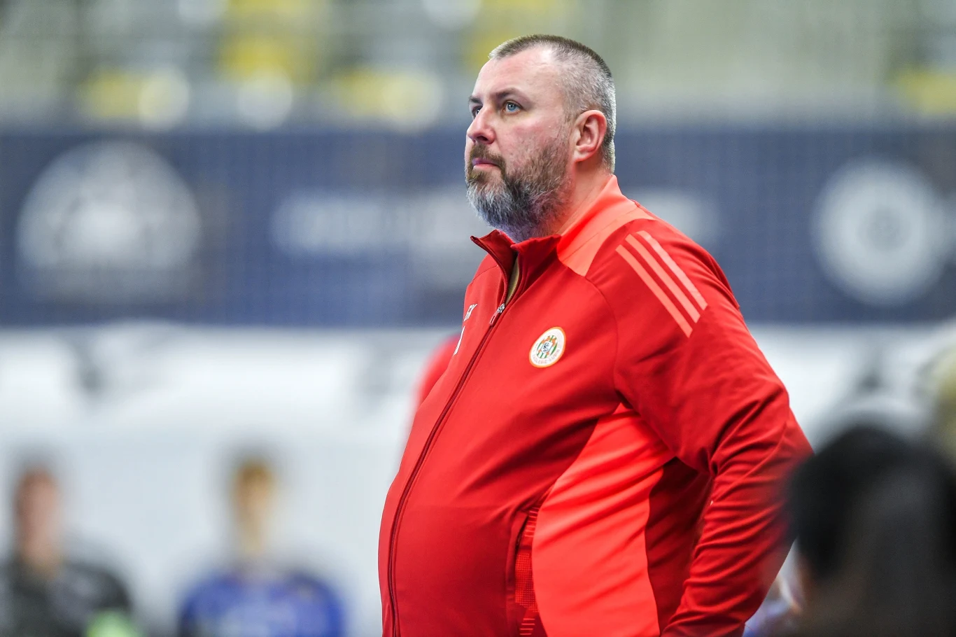 Grzegorz Klimczak Grzegorz Klimczak w czerwonym dresie na hali sportowej, stoi bokiem, krótkie włosy, broda.