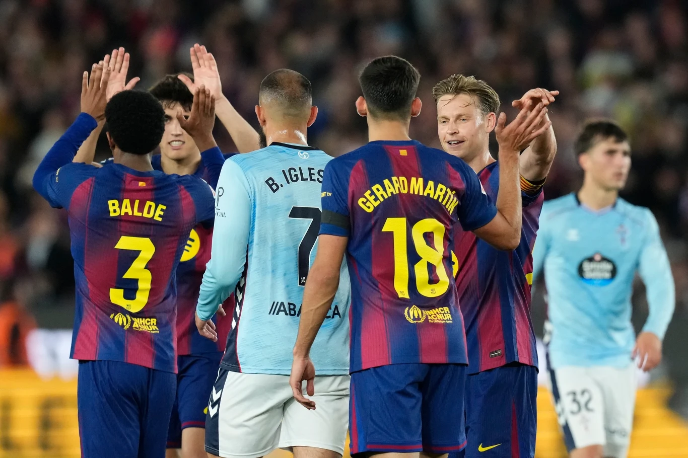 piłkarze dwóch drużyn na boisku w trakcie podziękowania lub przybijania piątek po zakończonym meczu, zawodnicy FC Barcelony ubrani w granatowo-bordowe stroje oraz gracze przeciwnej drużyny w jasnoniebieskich koszulkach, na pierwszym planie widoczne naz...
