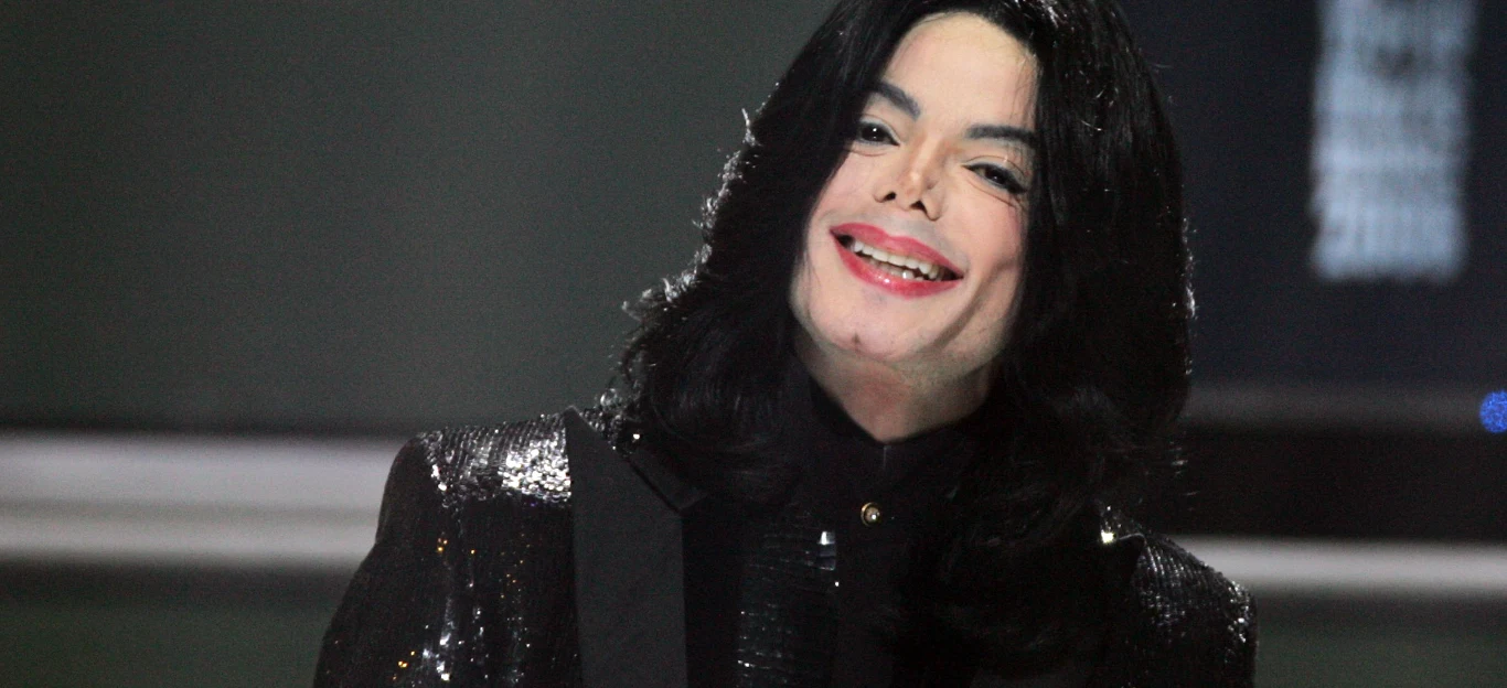 Michael Jackson w 2006 roku Michael Jackson w 2006 roku w ciemnej marynarce z cekinami, z długimi czarnymi włosami, na tle jasnego wnętrza