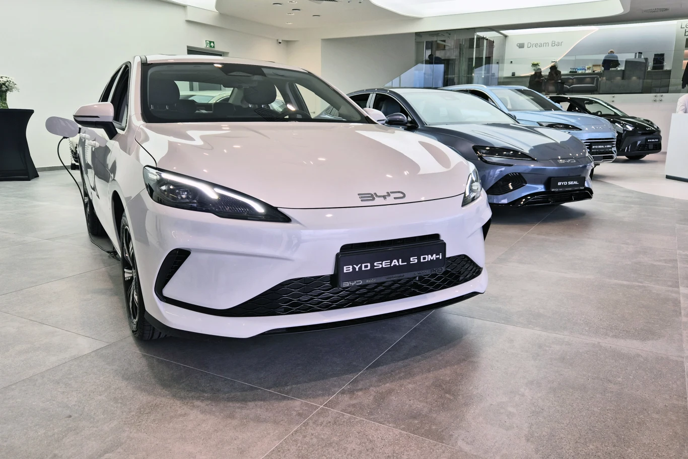 BYD jest jednym z chińskich koncernów, który w ostatnim czasie najbardziej urósł w Europie Biały BYD Seal S DM-i na pierwszym planie w salonie, w tle dwa inne auta marki BYD