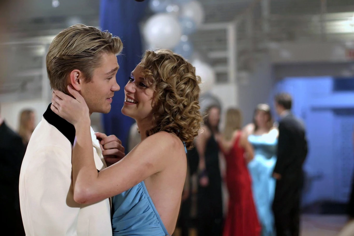 Hilarie Burton przez wiele lat grała w popularnych serialu młodzieżowym. Wcielała się w rolę Peyton Sawyer, które nie miała łatwej przeszłości Hilarie Burton jako Peyton Sawyer podczas balu, w niebieskiej sukni z partnerem w białym smokingu, w tle goście i balony