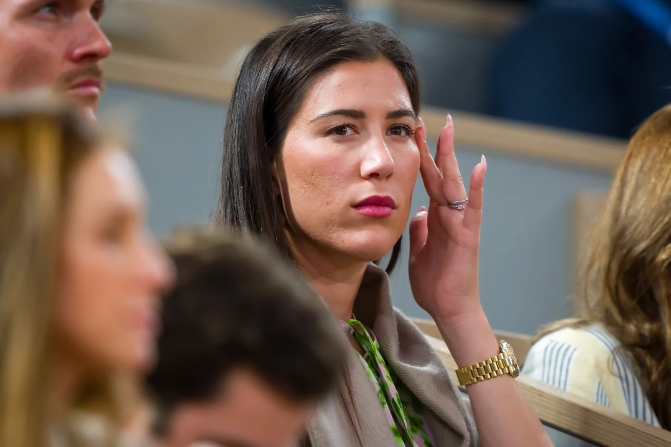 Garbine Muguruza Garbine Muguruza, elegancko ubrana, z ciemnymi włosami, siedzi w jasnym pomieszczeniu, z innymi w tle