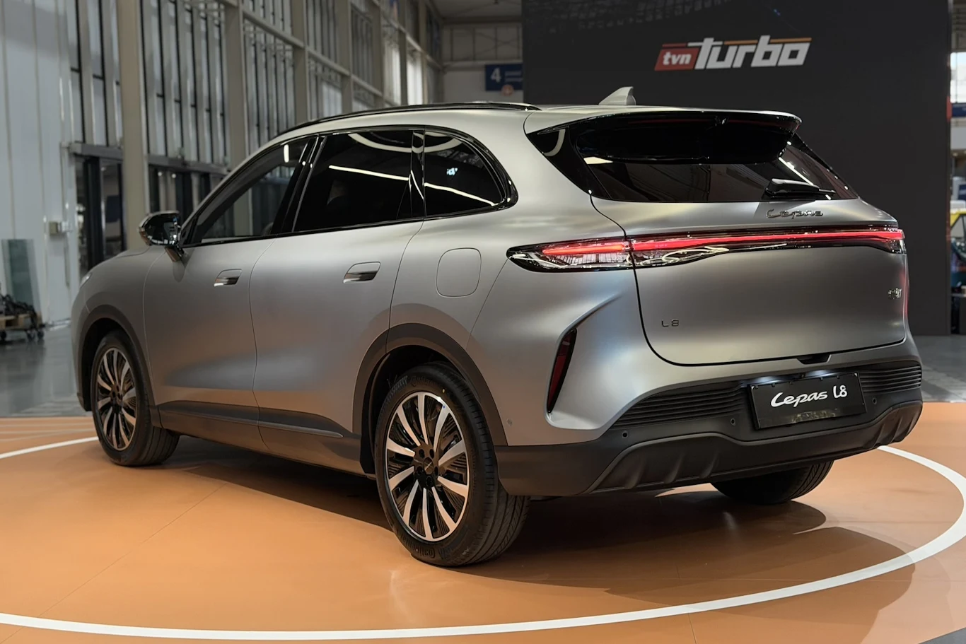 Lepas L8 srebrny SUV o nowoczesnych liniach nadwozia, charakterystyczny tylny pas świetlny LED, duże aluminiowe felgi i czarne przyciemniane szyby, samochód ustawiony na ekspozycji w jasnej hali
