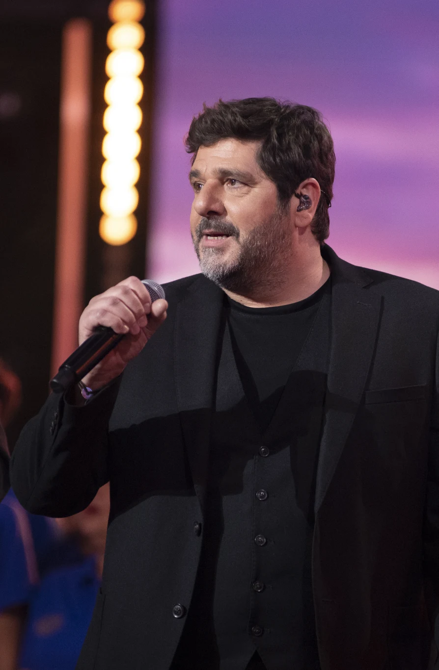 Patrick Fiori był gwiazdą wiosennej gali French Touch 2026 w Warszawie mężczyzna z krótkimi, ciemnymi włosami i brodą w czarnym garniturze, trzymający mikrofon i śpiewający na scenie; w tle rozmyte światło i sylwetki osób