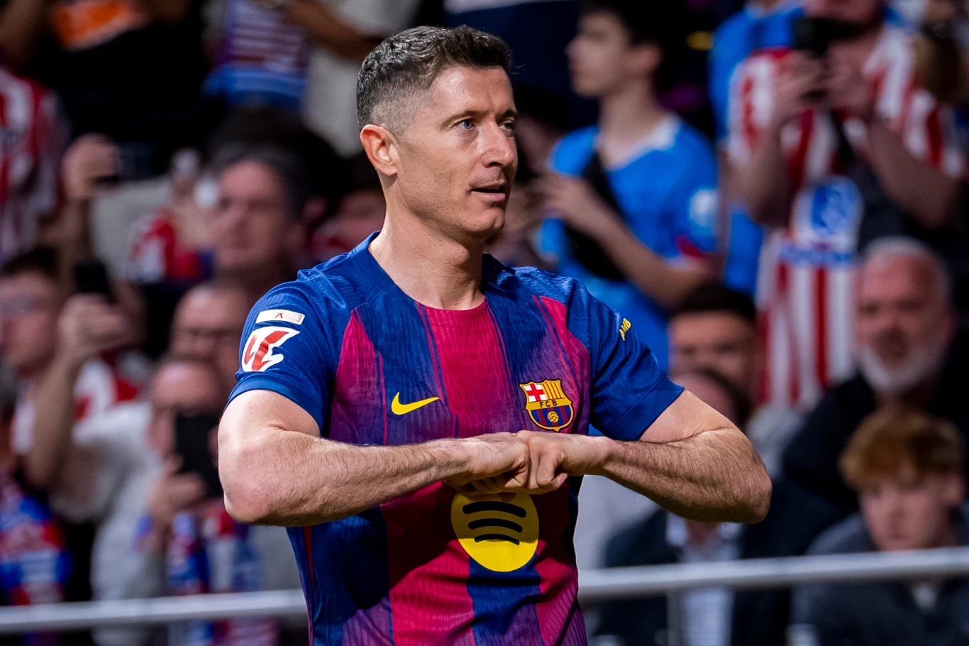 piłkarz w koszulce FC Barcelony wykonuje charakterystyczny gest rękami na tle kibiców i trybun stadionu