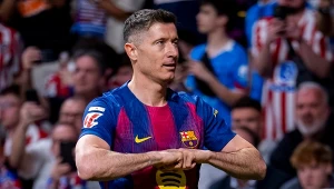 piłkarz w koszulce FC Barcelony wykonuje charakterystyczny gest rękami na tle kibiców i trybun stadionu