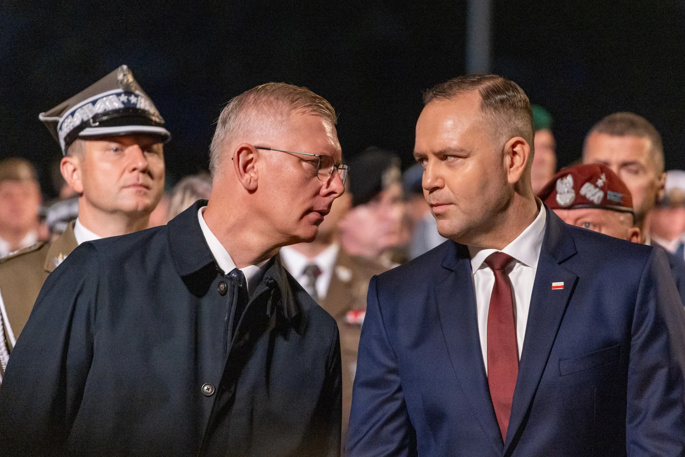 Prezydent RP Karol Nawrocki i Sławomir Cenckiewicz podczas rozmowy Prezydent Karol Nawrocki i Sławomir Cenckiewicz rozmawiają wśród wojskowych podczas oficjalnego wydarzenia.