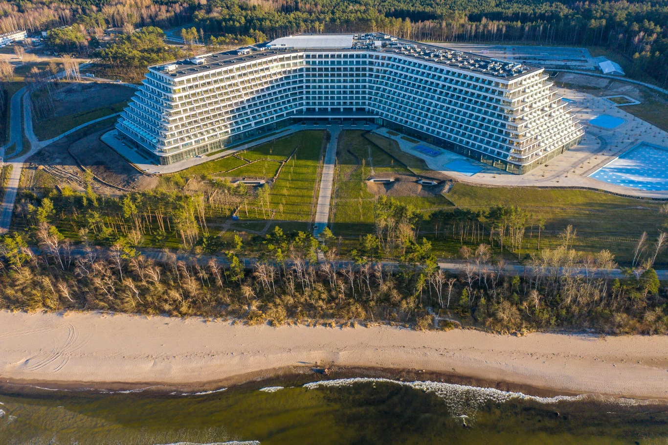 Budowa hotelu w Pobierowie rozpoczęła się w 2018 roku nowoczesny, rozległy budynek o półokrągłym kształcie usytuowany tuż przy plaży z szerokim pasem piasku, otoczony lasem sosnowym, z widocznymi alejkami prowadzącymi w kierunku wejścia do obiektu