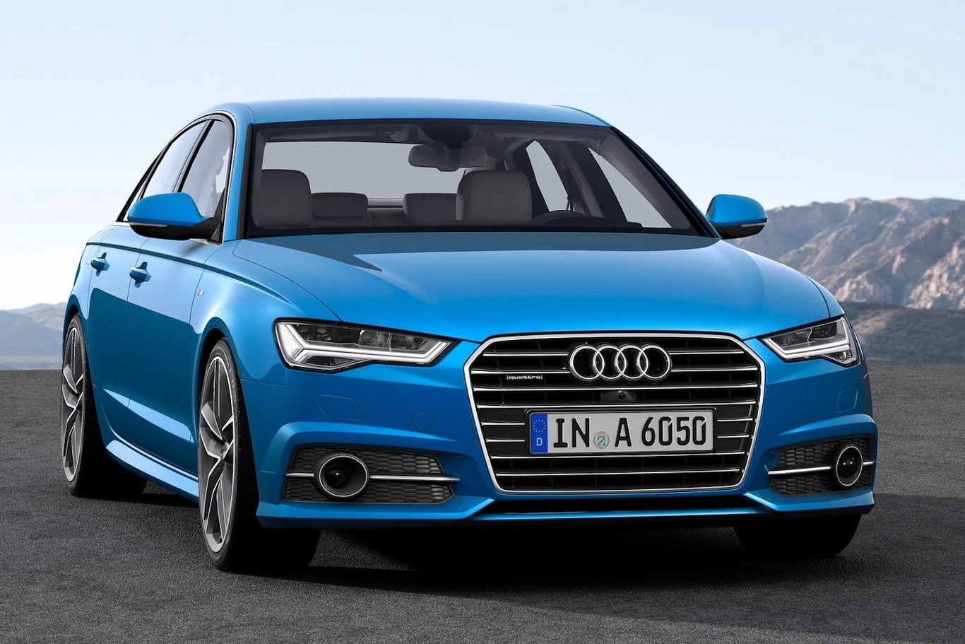 Audi A6 rocznik 2015 niebieskie Audi A6 zaparkowane na asfalcie, widok z przodu podkreślający charakterystyczny grill z logo Audi, nowoczesne reflektory LED oraz dynamiczną linię nadwozia; w tle górzysty krajobraz