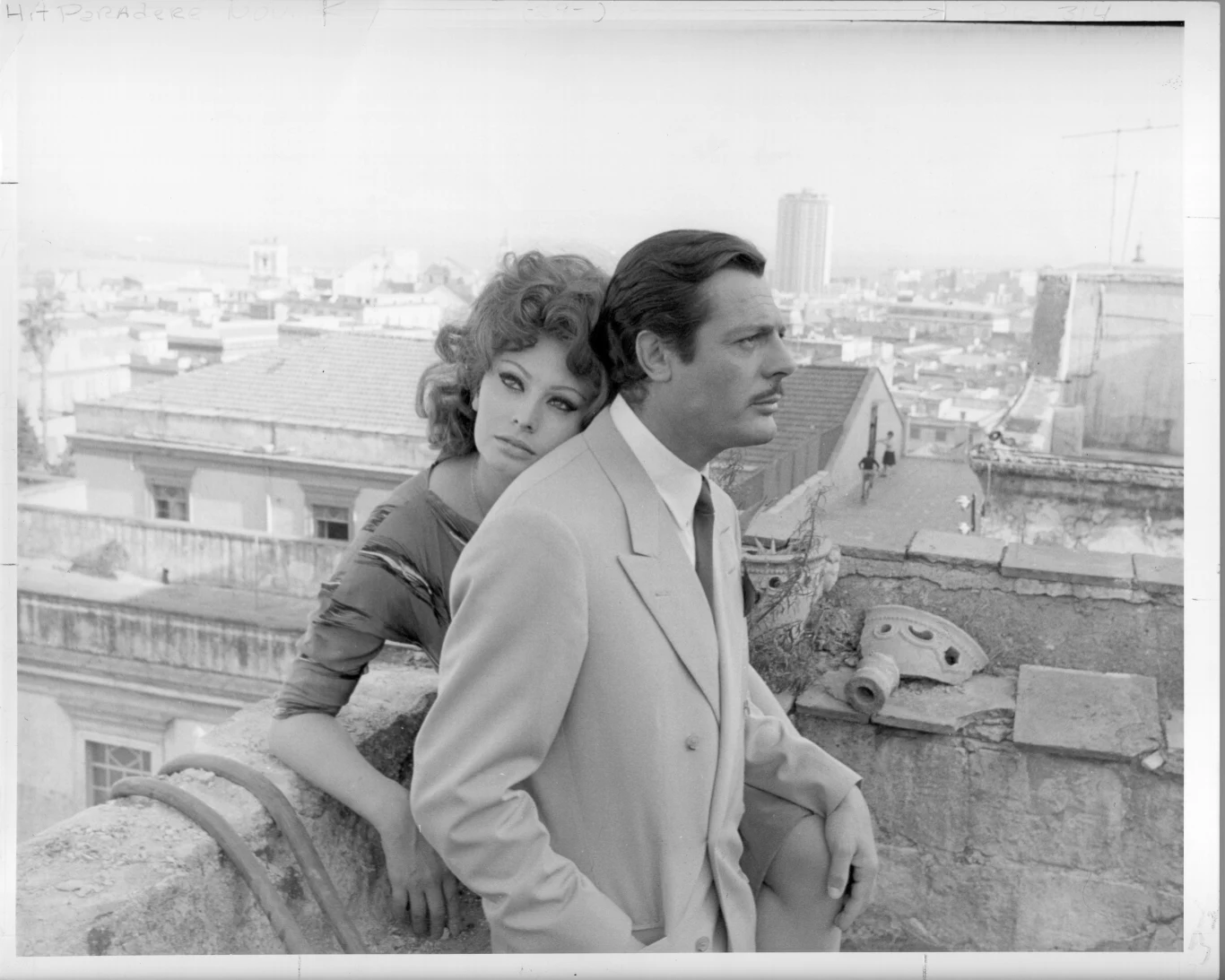 Sophia Loren i Marcello Mastroianni kobieta obejmuje mężczyznę stojącego na dachu, oboje patrzą w różne strony z poważnymi wyrazami twarzy, w tle rozległa panorama miejskich budynków