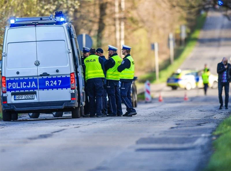 Łukasz Litewka zginął w wypadku grupa policjantów w odblaskowych kamizelkach stoi przy radiowozie z napisem „policja” zaparkowanym na poboczu drogi, w tle widoczny drugi radiowóz oraz rozstawione pachołki sygnalizujące zabezpieczony teren