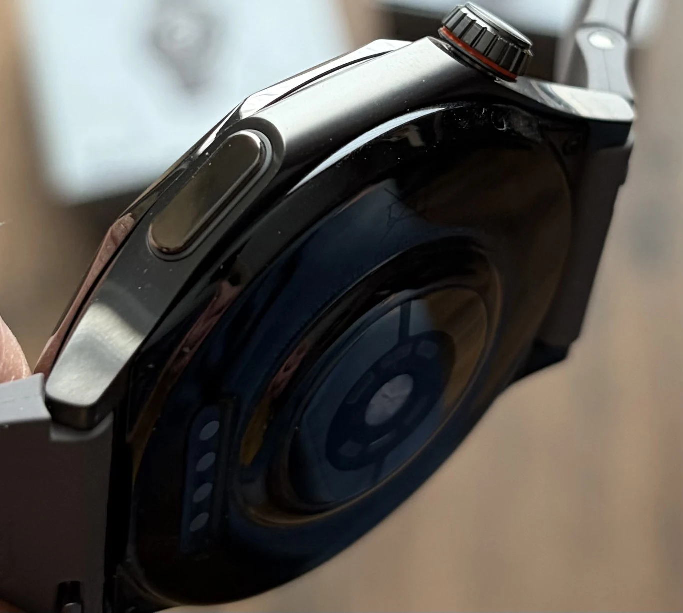 Nowy smartwatch Oppo prezentuje się bardzo dobrze i producent przyłożył uwagę do najdrobniejszych szczegółów. czarny smartwatch z widocznym spodem obudowy, okrągłym sensorem do pomiaru parametrów zdrowotnych oraz przyciskiem bocznym i obrotową koronką