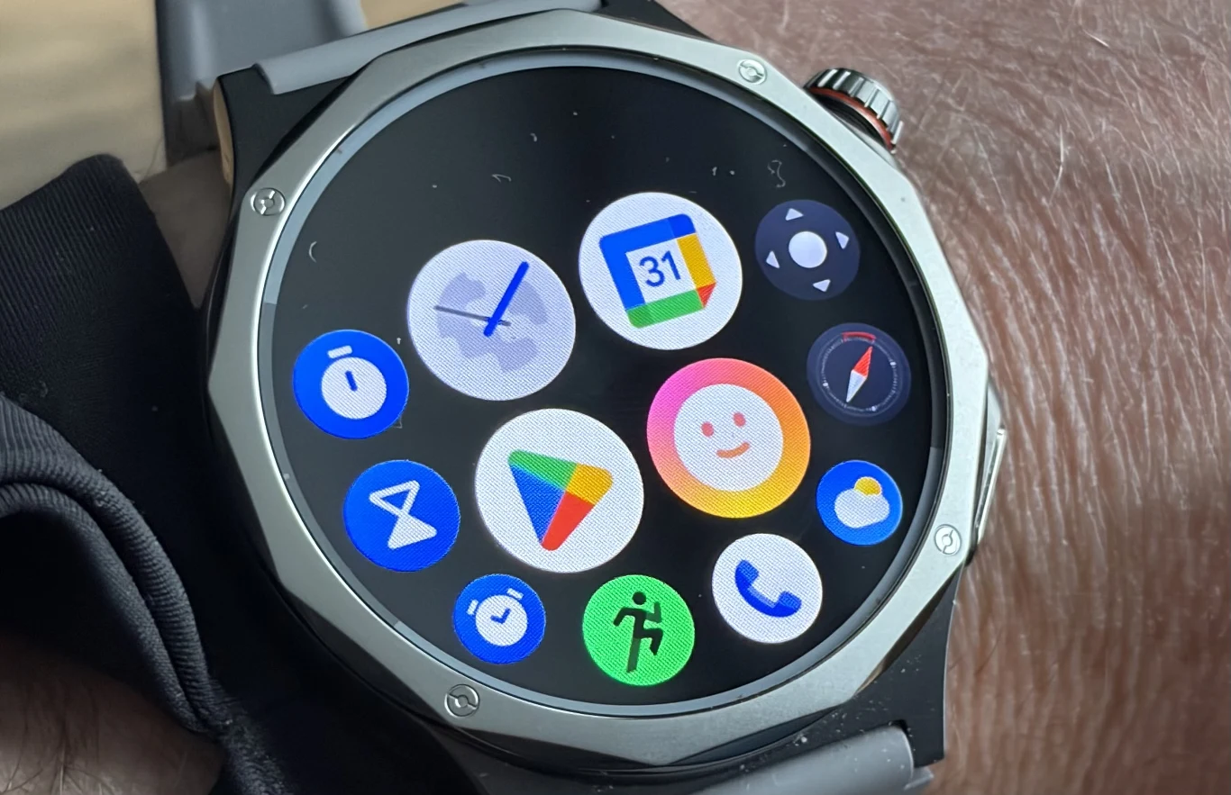 Oppo Watch X3 pracuje pod kontrolą Wear OS 6 i zapewnia głęboką integrację z ekosystemem Google. nowoczesny smartwatch z okrągłym ekranem dotykowym, wyświetlający kolorowe ikony popularnych aplikacji takich jak zegar, kalendarz Google, Google Play, telefon oraz aplikacje fitness; widoczny metalowy pierścień wokół ekranu i fragment opaski na nadgar...