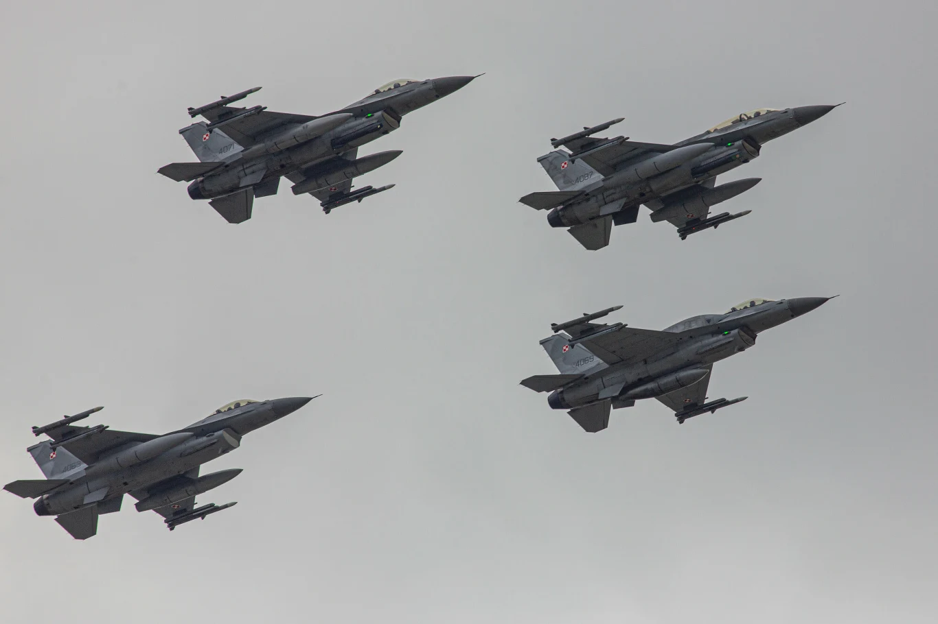Polskie samoloty F-16 Cztery myśliwce F-16 Sił Powietrznych lecące w formacji na tle zachmurzonego nieba