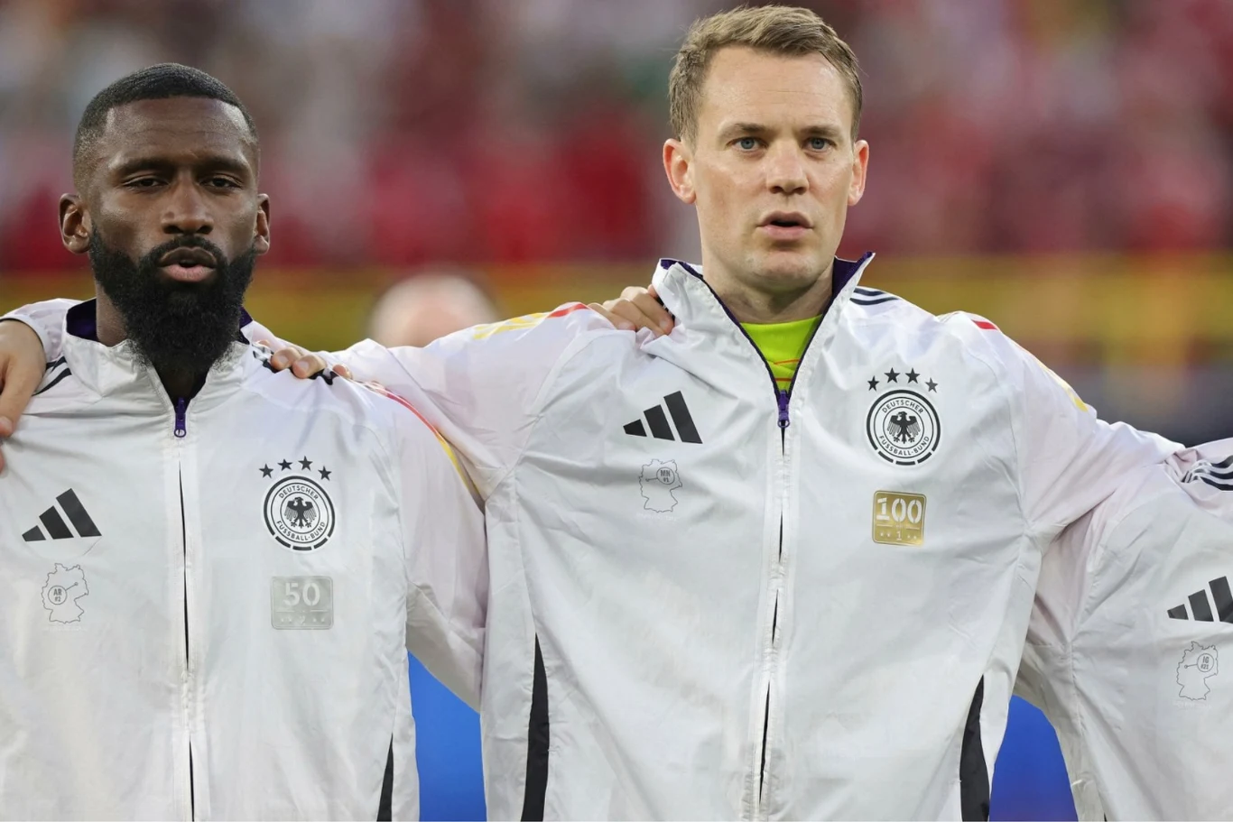 Manuel Neuer (z prawej) nie gra już w reprezentacji Niemiec, ale za to wciąż zachwyca jako bramkarz Bayernu Monachium Manuel Neuer i drugi piłkarz Niemiec w białych kurtkach z herbem stoją razem przed meczem