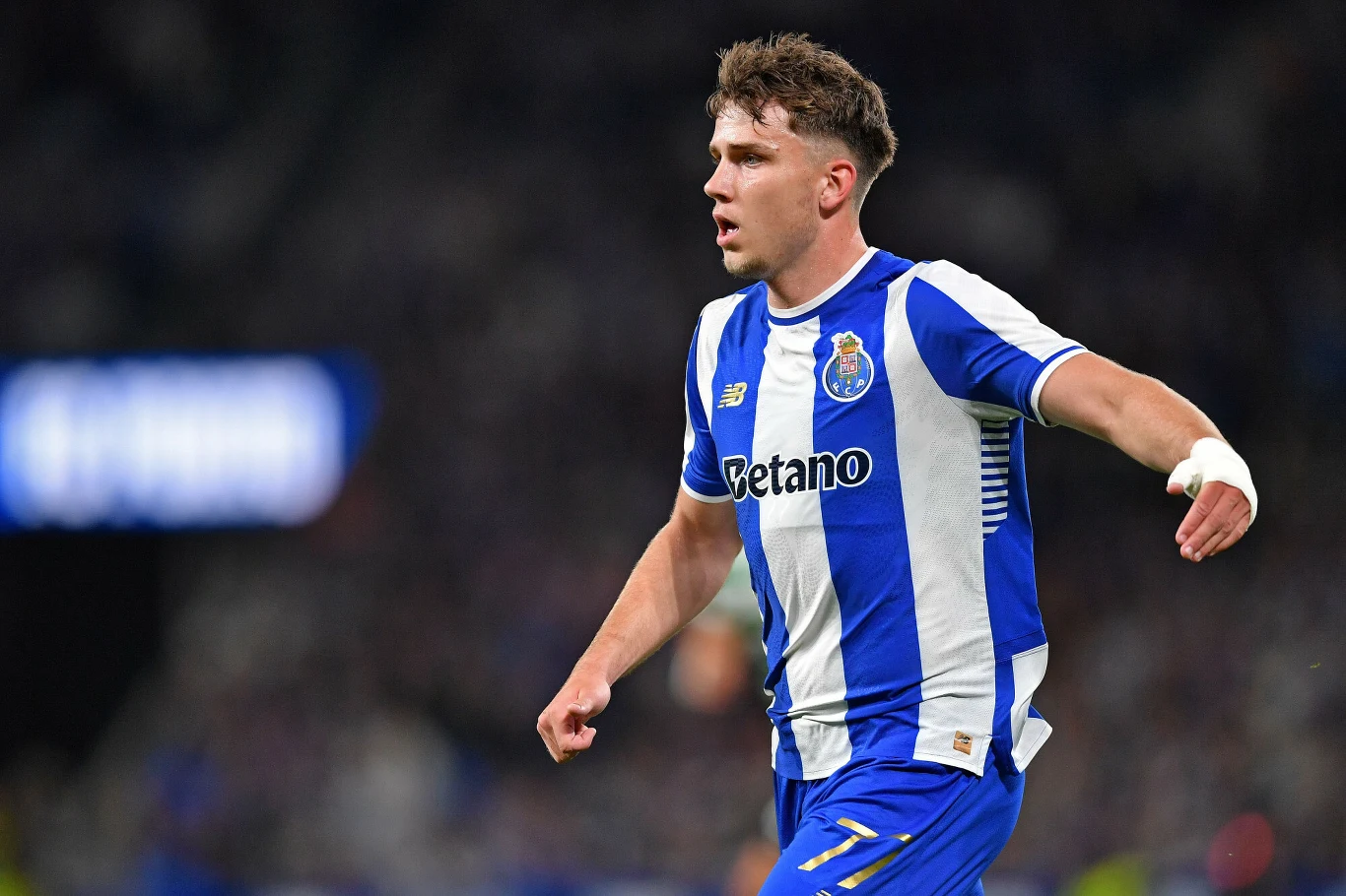 piłkarz w niebiesko-białej koszulce FC Porto biegnący podczas meczu, z wyraźną koncentracją na twarzy, z opaską na prawym nadgarstku