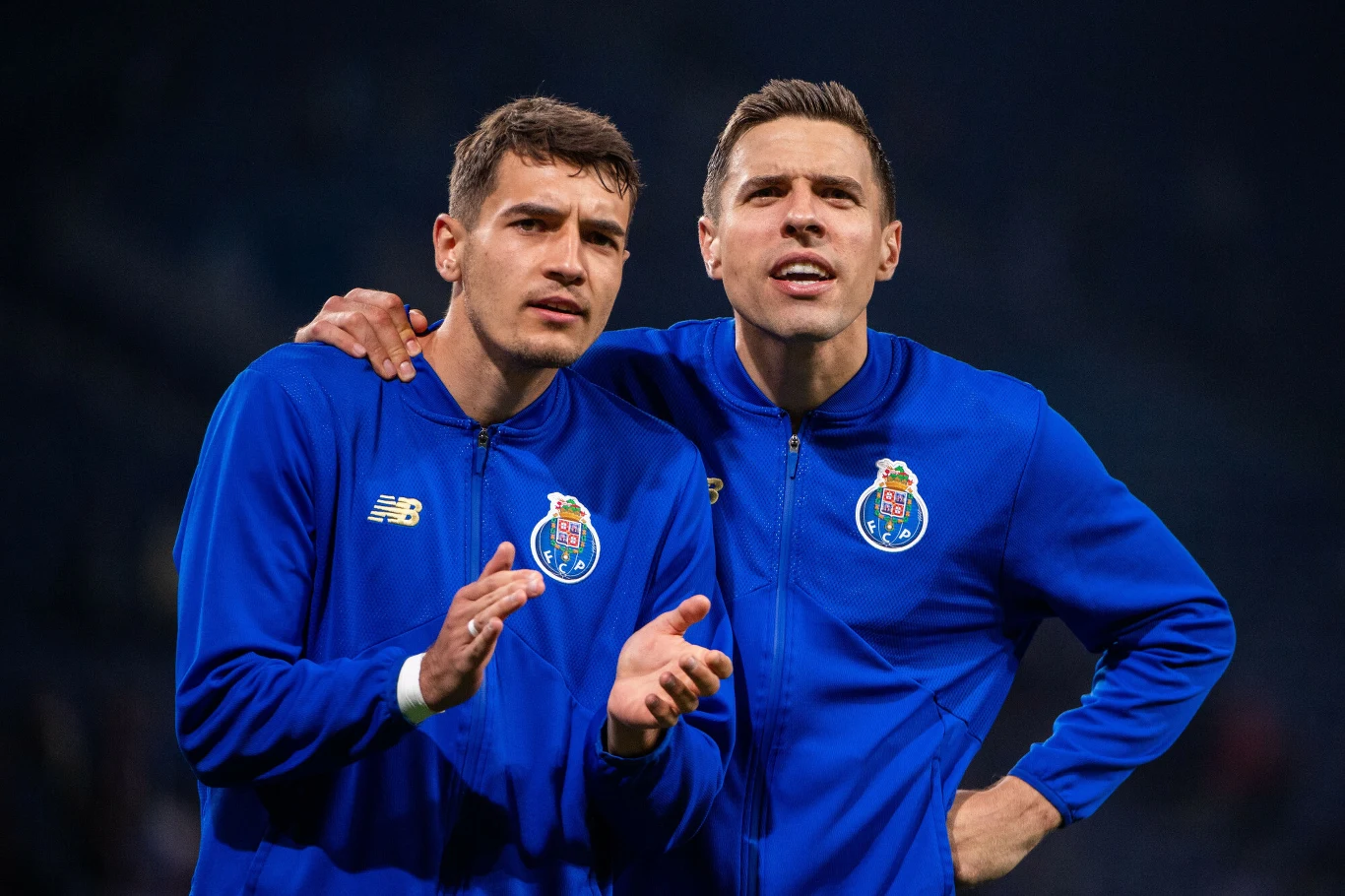 Jakub Kiwior i Jan Bednarek dwóch piłkarzy w niebieskich dresach FC Porto z emblematem klubu na piersi stoi blisko siebie, jeden z nich obejmuje drugiego, obaj koncentrują się na wydarzeniach przed sobą