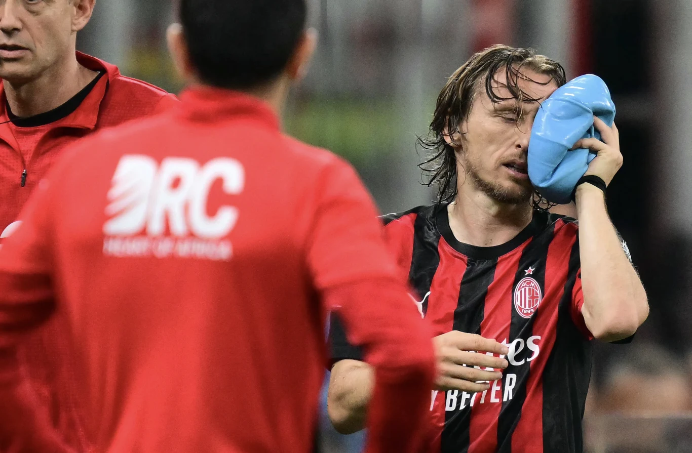 Luka Modrić nie dotrwał do końcowego gwizdka piłkarz w czerwono-czarnej koszulce AC Milan przykłada worek z lodem do twarzy, wokół niego znajdują się członkowie sztabu medycznego ubrani na czerwono