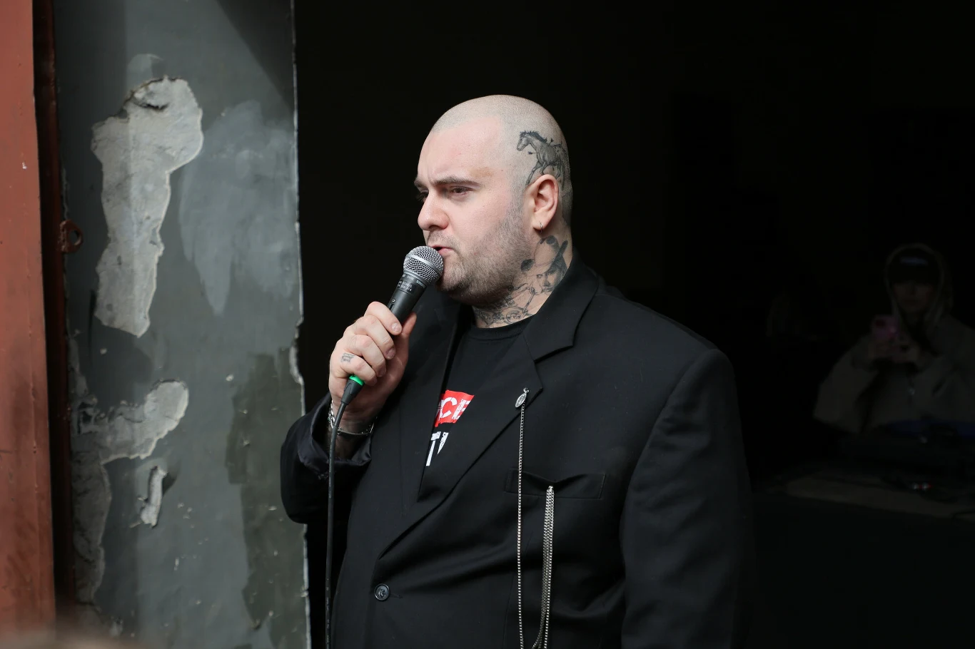 Bedoes rozkręcił akcję na rzecz fundacji Cancer Fighters razem z Łatwogangiem Bedoes podczas akcji z Łatwogangiem: łysy mężczyzna z tatuażami, mikrofonem, w czarnej marynarce i łańcuchem.
