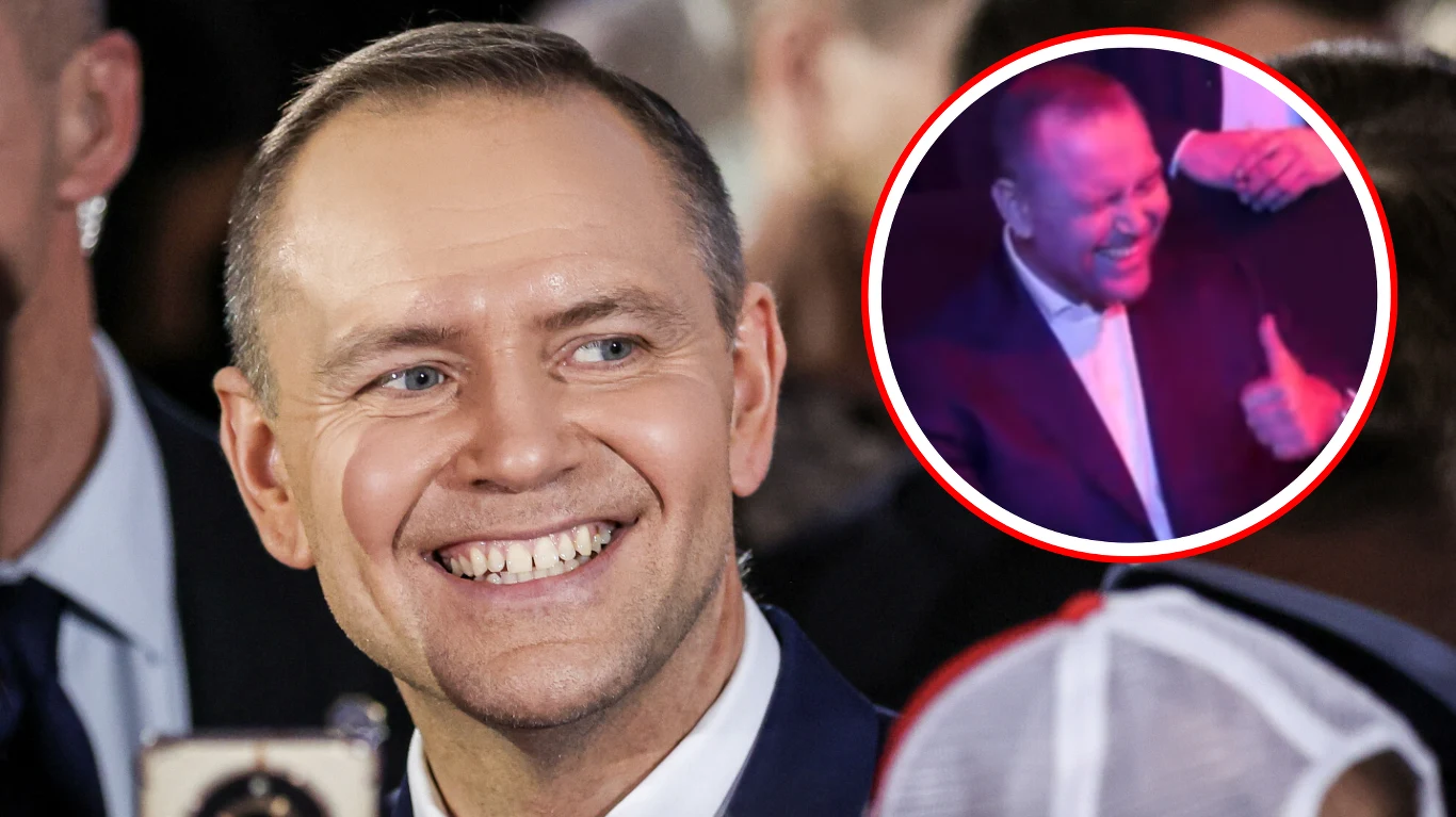 uśmiechnięty mężczyzna w garniturze w centrum uwagi, otoczony przez ludzi, zbliżenie na jego roześmianą twarz, w prawym górnym rogu okrągła wstawka ukazująca go pokazującego znak 'kciuk w górę'