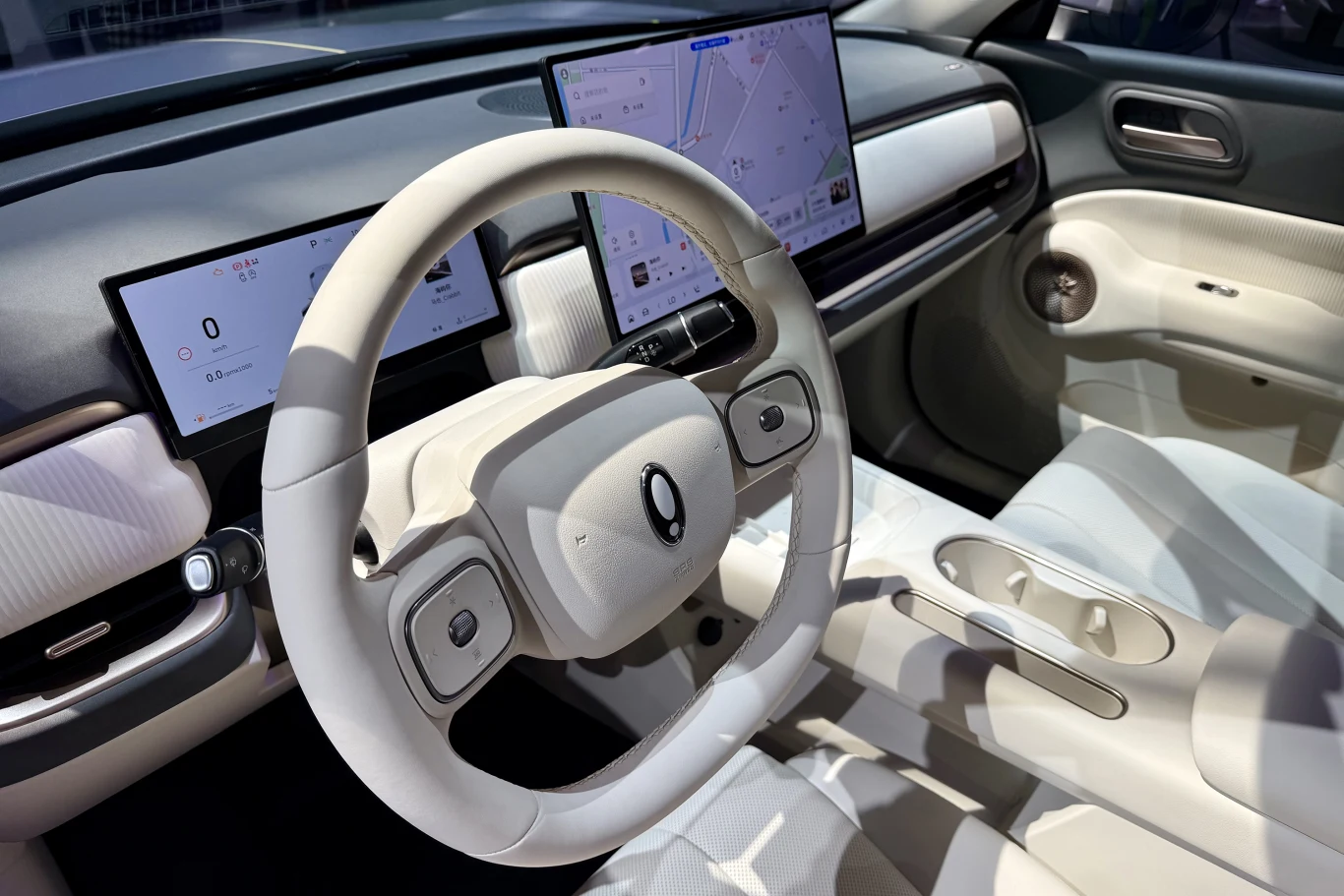 Jasne, nowoczesne wnętrze samochodu elektrycznego z minimalistyczną deską rozdzielczą, dwoma dużymi wyświetlaczami cyfrowymi i kierownicą w futurystycznym stylu.