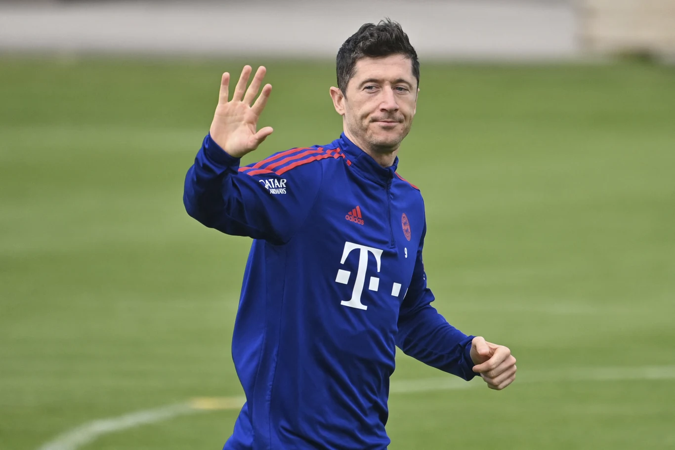 Robert Lewandowski za czasów gry w Bayernie Monachium pobił rekord Bundesligi w liczbie goli strzelonych w jednym sezonie. Czy Harry Kane wkrótce przebije jego wynik? Robert Lewandowski w niebieskim dresie Bayernu Monachium na murawie, unosi rękę w geście powitania
