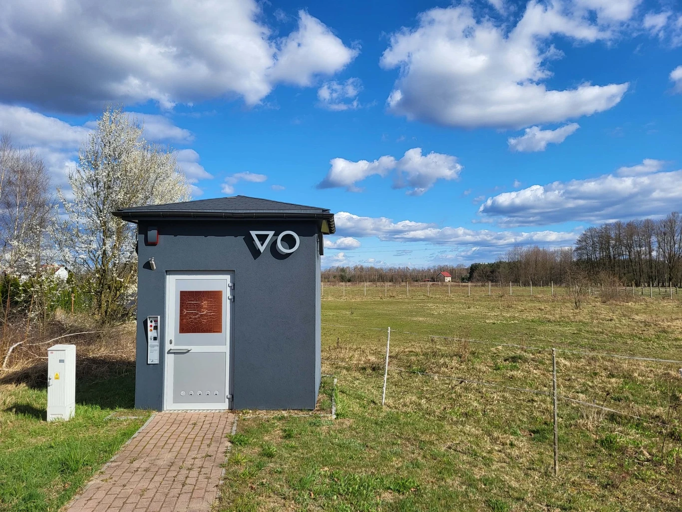 Toaleta publiczna na końcu wsi Zakęcie (woj. lubuskie) bierze udział w plebiscycie na najgorzej wydane publiczne pieniądze Nowoczesna toaleta publiczna w Zakęciu, budynek z ciemnoszarą elewacją przy polnej drodze, obok skrzynka elektryczna