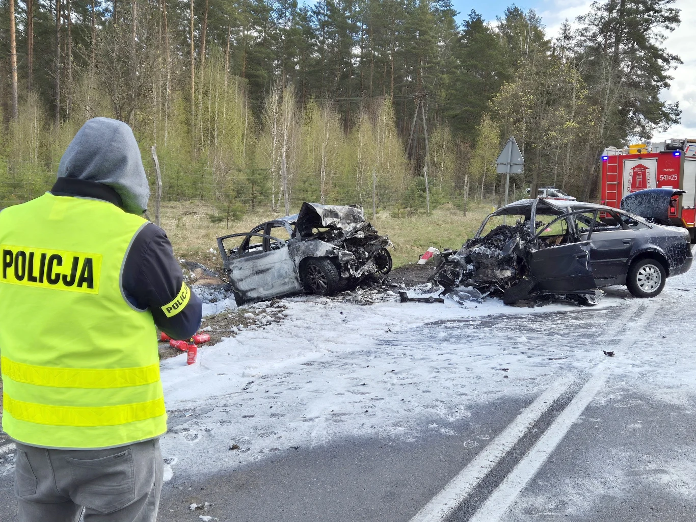 Tragiczny wypadek na Mazurach. Są nowe informacje Dwa rozbite samochody po zderzeniu na drodze nr 58, jeden spalony, policjant dokumentuje zdarzenie