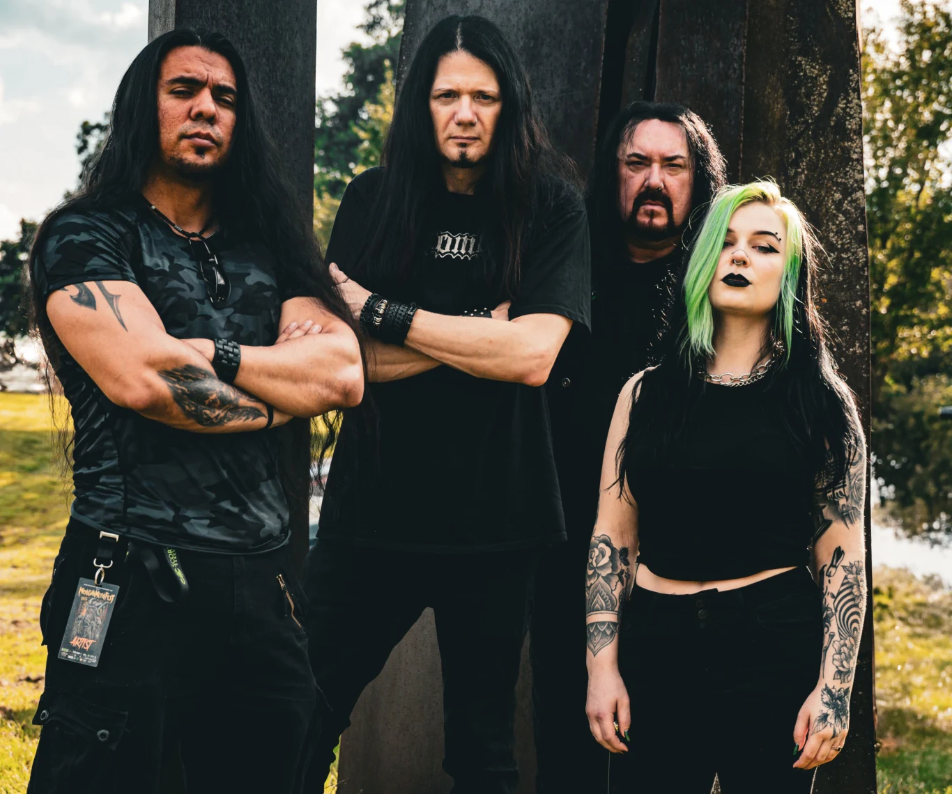 Embryonic Autopsy przed premierą Embryonic Autopsy w rockowych stylizacjach, w plenerze przy dużej rzeźbie, ubrani na czarno, z tatuażami.