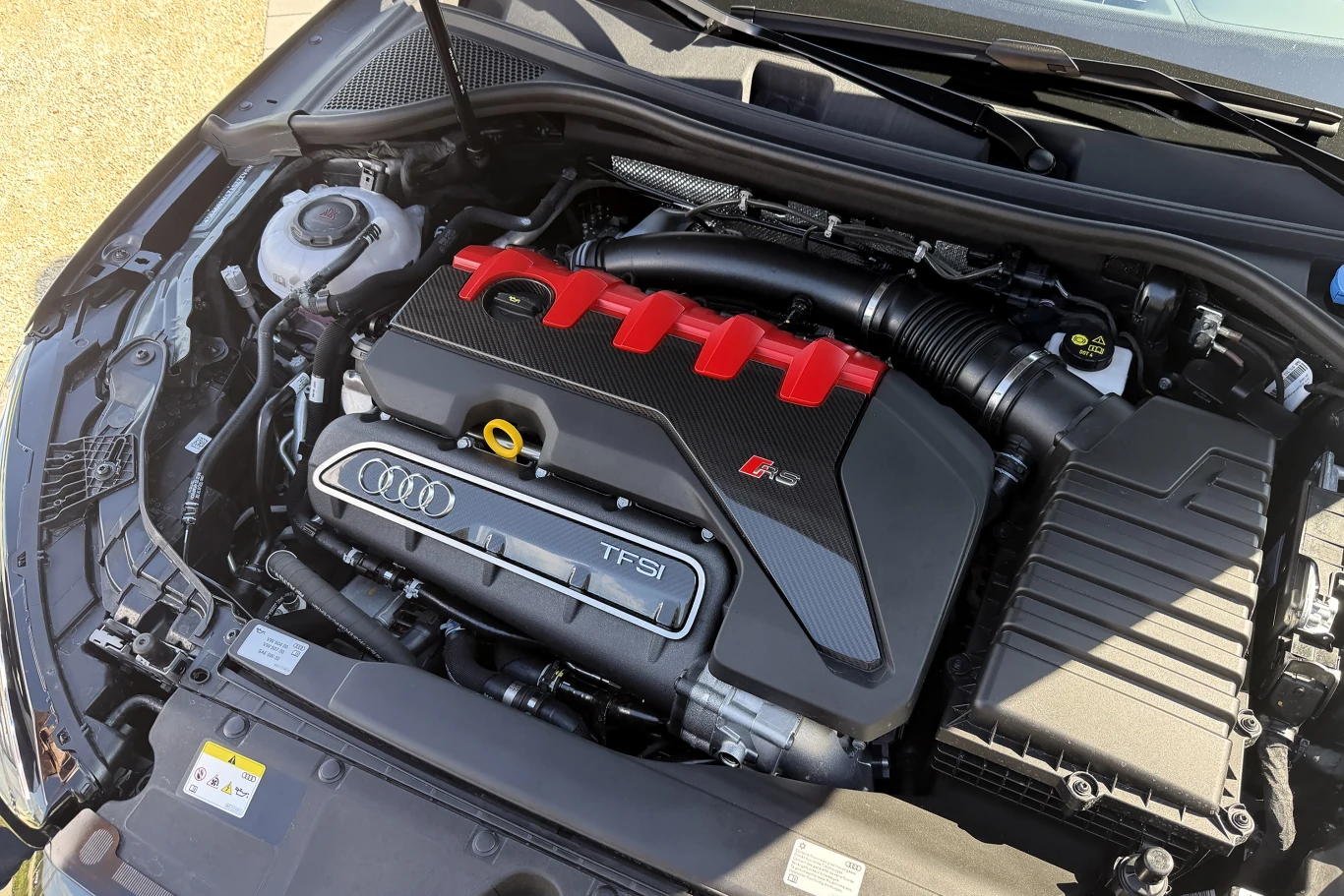 Dobrze znany silnik 2.5 TFSI. W przypadku RS3 Competition Limited zapewnia on 400 KM i 500 Nm silnik samochodowy Audi z widocznym oznaczeniem TFSI i emblematem RS, elementy osłony silnika w kolorze czarnym z czerwonym akcentem oraz logo czterech pierścieni, wyeksponowany kolektor dolotowy i zbiornik płynu chłodzącego po lewej stronie