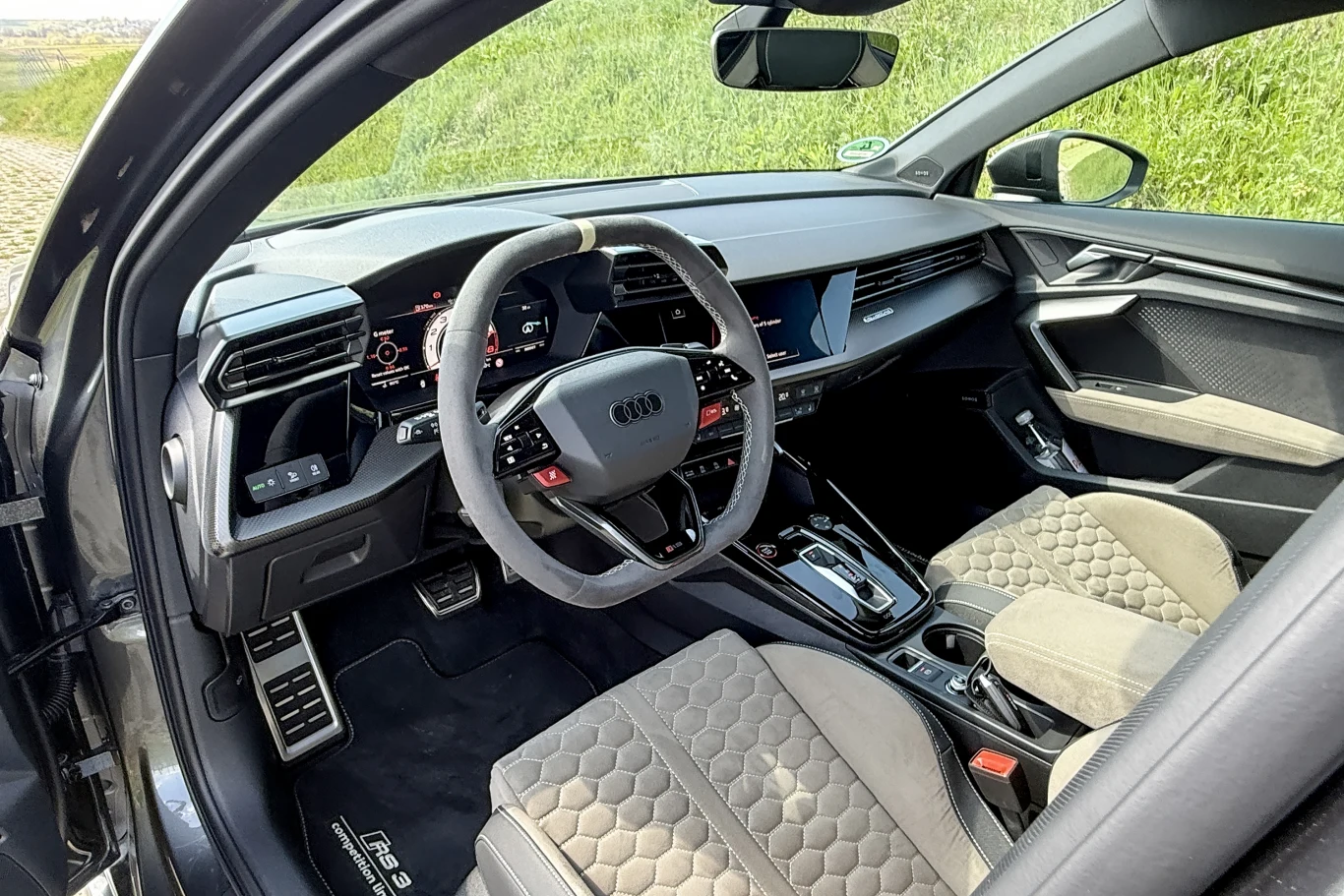 Spore wrażenie robi połączenie czarno-kremowej skórzanej tapicerki. nowoczesne wnętrze samochodu marki Audi z cyfrowym zestawem wskaźników, sportową kierownicą obszytą alkantarą oraz fotelami o charakterystycznym, pikowanym wzorze