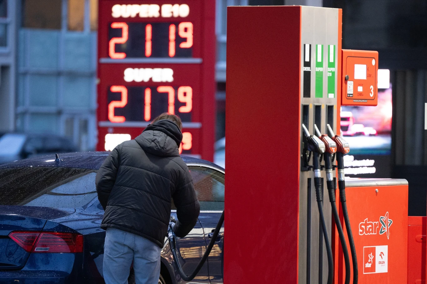 Niemcy walczą z rosnącymi cenami paliw. Mechanizm ochronny przyniósł skutek odwrotny od zamierzonego Mężczyzna tankuje samochód przy czerwonym dystrybutorze, w tle tablice z cenami paliw na stacji w Niemczech