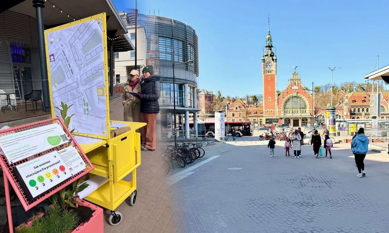 interaktywny punkt informacyjny z mapą umieszczony na żółtym stojaku, w tle przestrzeń miejska z grupą przechodniów oraz charakterystycznym budynkiem dworca kolejowego z wysoką wieżą i zegarem