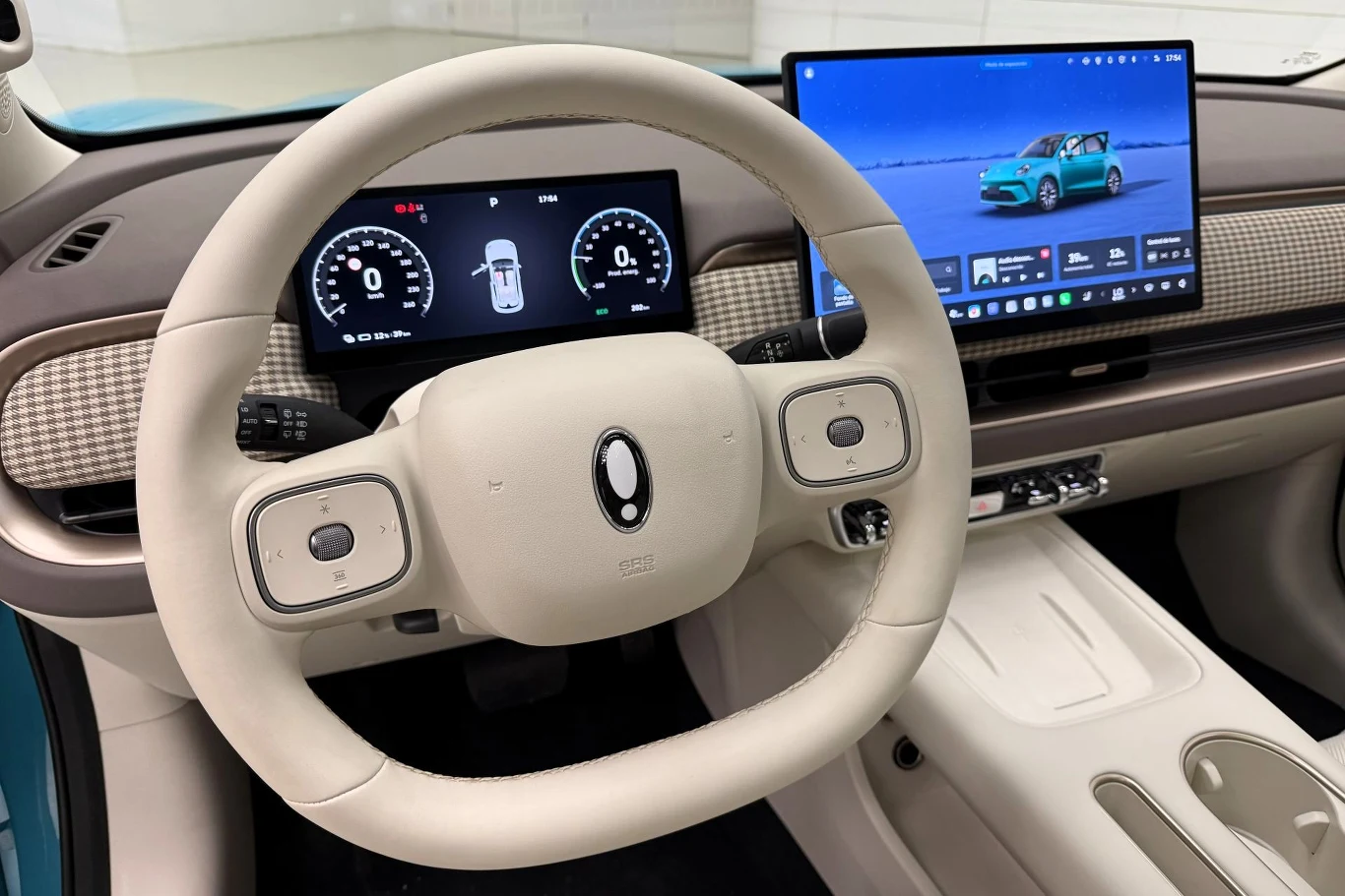 Great Wall Motor zwraca uwagę, że ekran multimediów ma największą w swojej klasie szerokość. jasnobeżowa, nowoczesna kierownica z prostokątnymi przyciskami po bokach, dwa cyfrowe ekrany: jeden za kierownicą z wskaźnikami prędkości i baterii, drugi po prawej strony prezentuje komputer pokładowy z grafiką pojazdu, wnętrze o minimalistycznym desi...