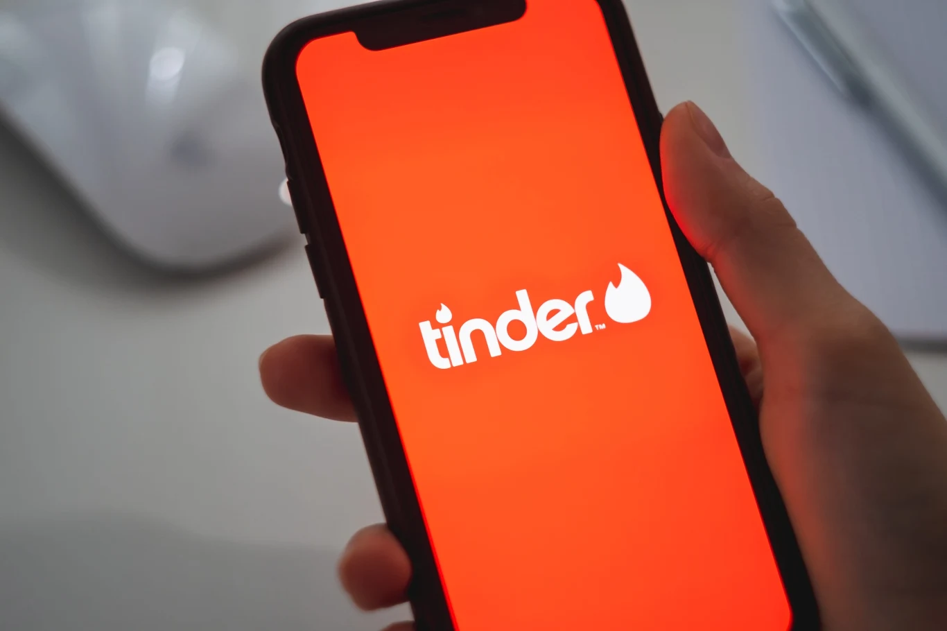 Milena przyznaje, że na Tinderze często "zaczepiają" ją młodsi mężczyźni ekran smartfona z wyświetlonym logo aplikacji Tinder na czerwonym tle, trzymany w prawej dłoni