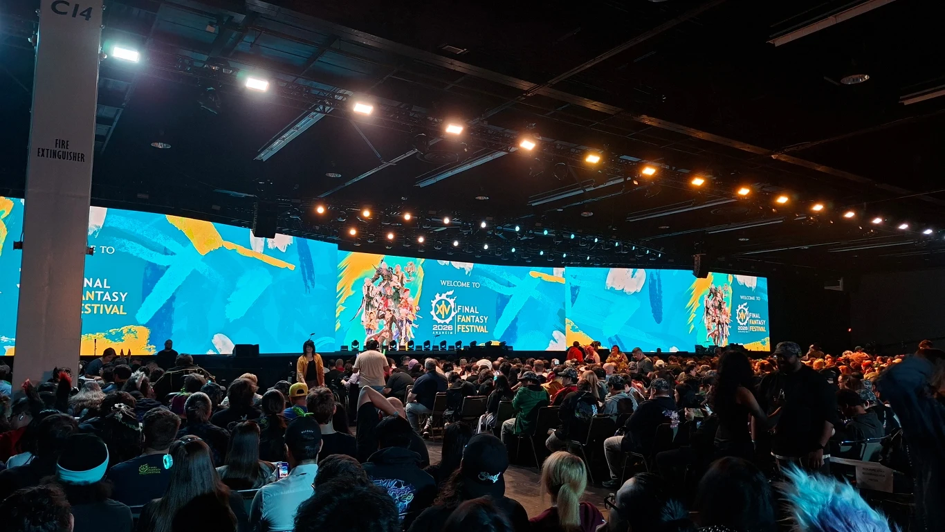 źródło: Tomasz Alicki Tłum ludzi siedzących zwrócony w stronę ogromnego, kolorowego ekranu LED z logo Final Fantasy XIV Fan Festival oraz grafikami z gry, scena oświetlona profesjonalnym światłem, atmosfera oczekiwania na wydarzenie związane z grami komputerowymi.