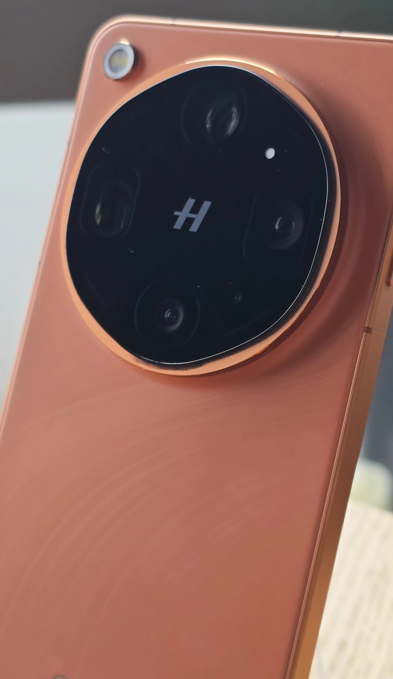 Oppo postawiło na współpracę z Hasselblad. Pomarańczowy smartfon z dużą, okrągłą wyspą aparatów fotograficznych z logo Hasselblad pośrodku oraz pojedynczą diodą obok modułu kamer.