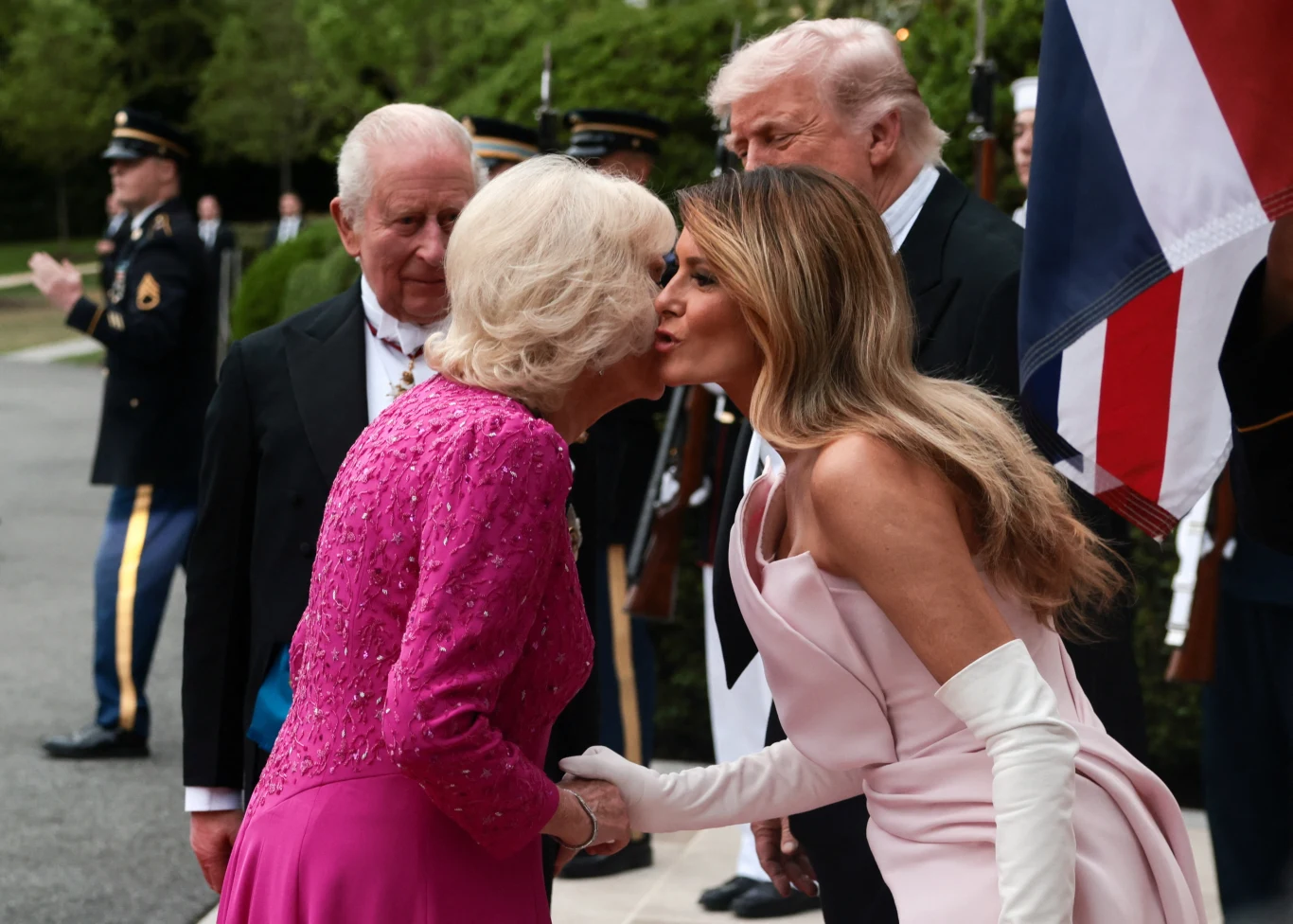 Królowa Camilla podczas wizyty w Białym Domu nie zdecydowała się na założenie tiary, tak jak Elżbieta II w 2007 roku Królowa Camilla i Melania Trump witają się pocałunkiem w policzek podczas bankietu w Białym Domu, w tle flagi i żołnierze.