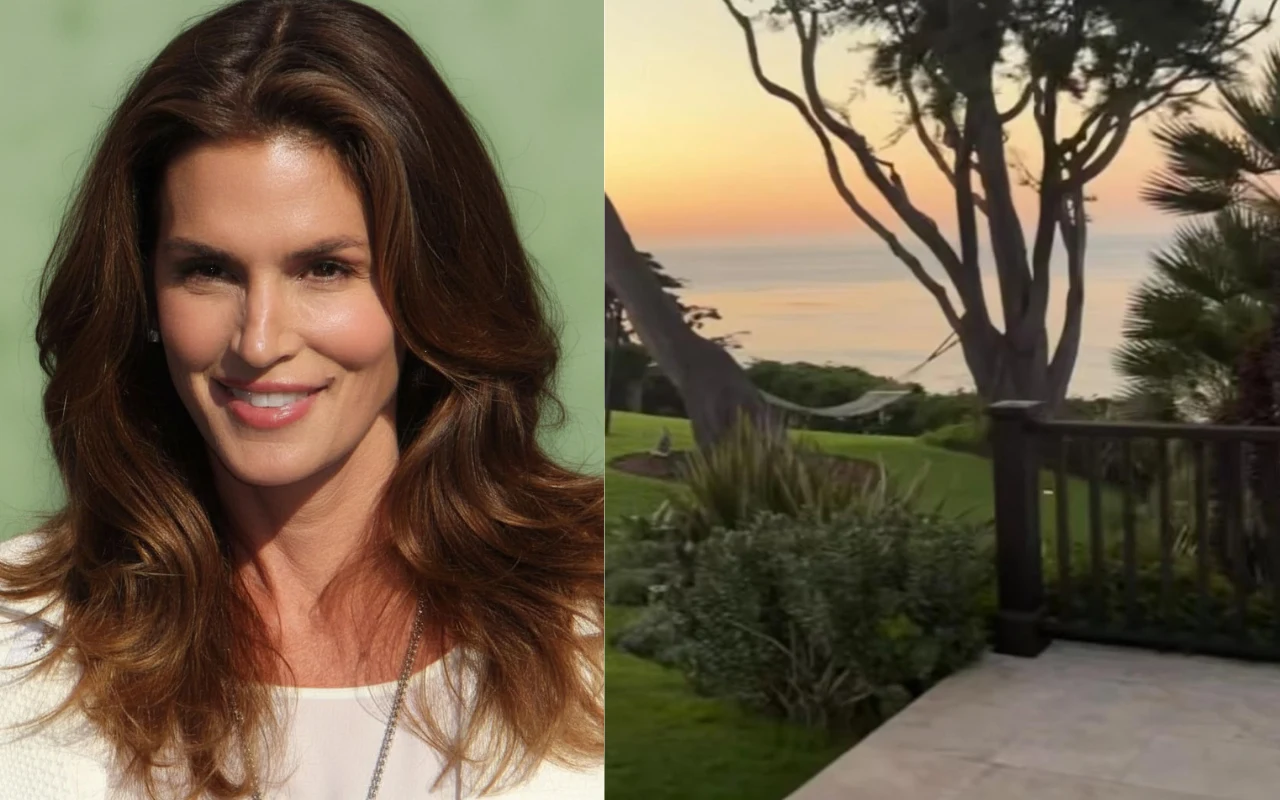 Kobieta o brązowych włosach i jasnej cerze uśmiecha się, ubrana w białą bluzkę; po prawej stronie widok na ogród z zieloną trawą, bujną roślinnością i rozciągającym się w tle morzem oraz zachodem słońca za drzewami.