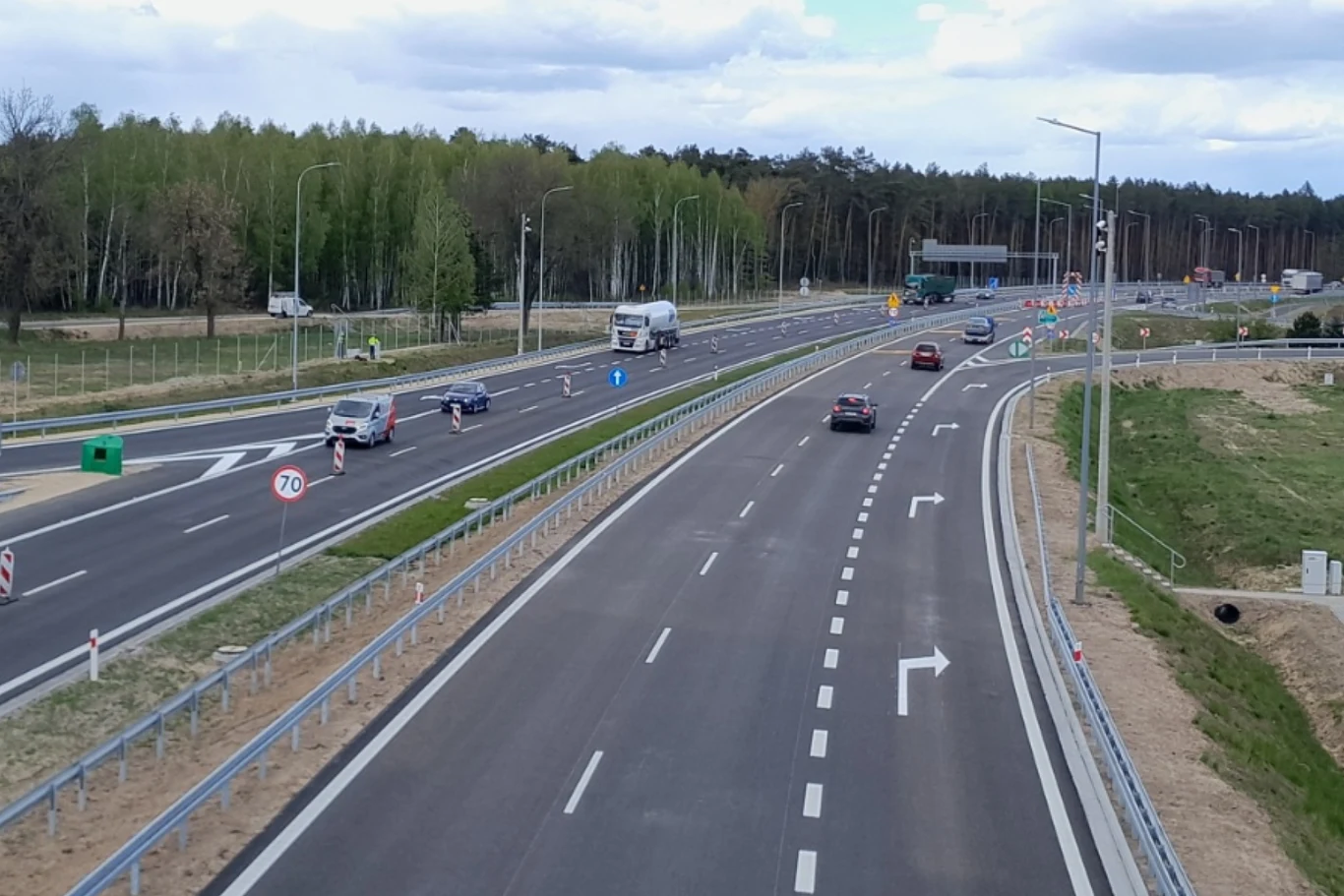 Kierowcy mogą od dziś korzystać z dwujezdniowej obwodnicy Kocka w ciągu drogi ekspresowej S19. Dwujezdniowa obwodnica Kocka na S19; auta osobowe i ciężarówka na nowoczesnej trasie, otoczenie leśne i zabudowania.